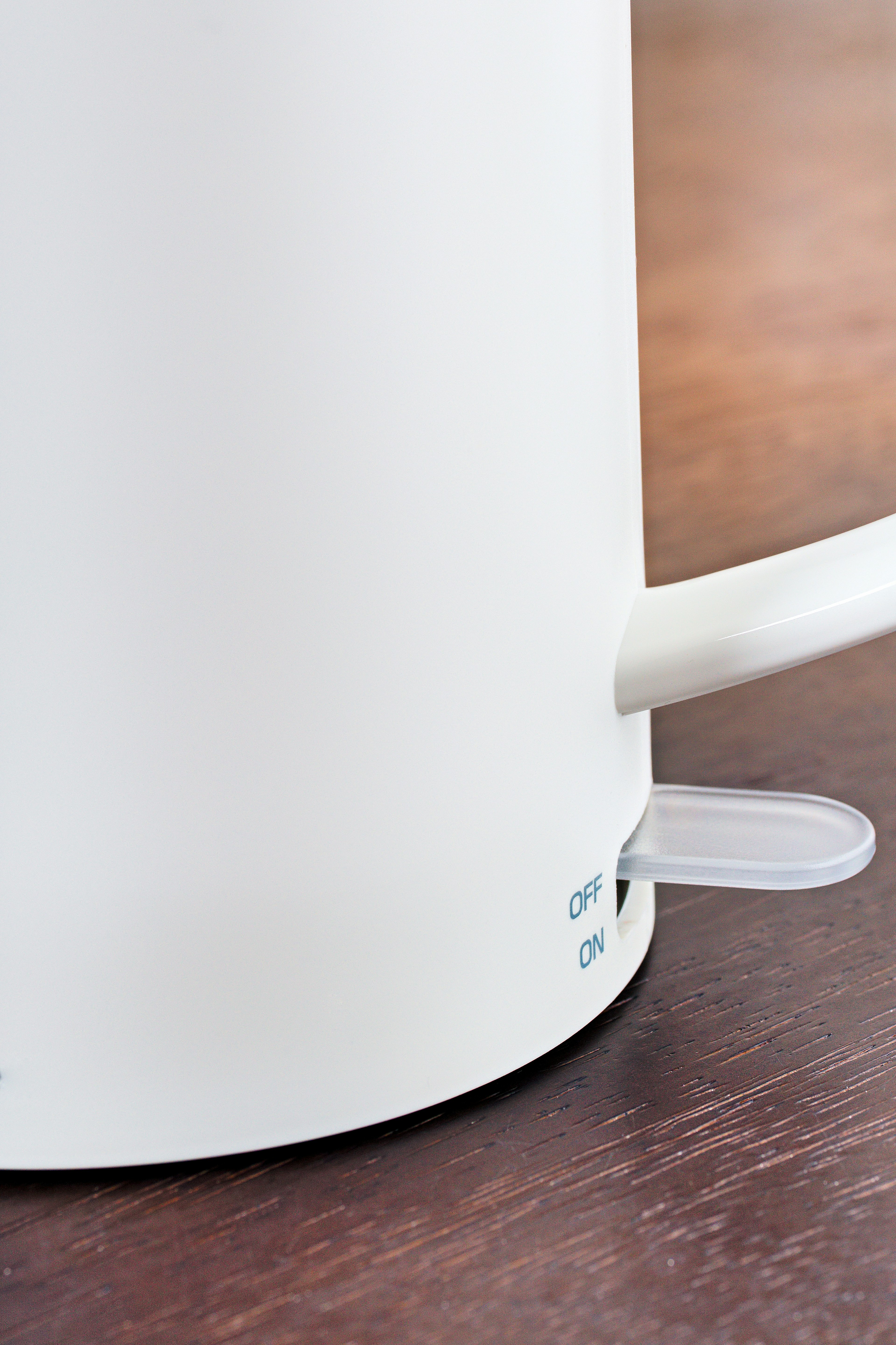 Close-up of a white electric kettle featuring a switch and cord