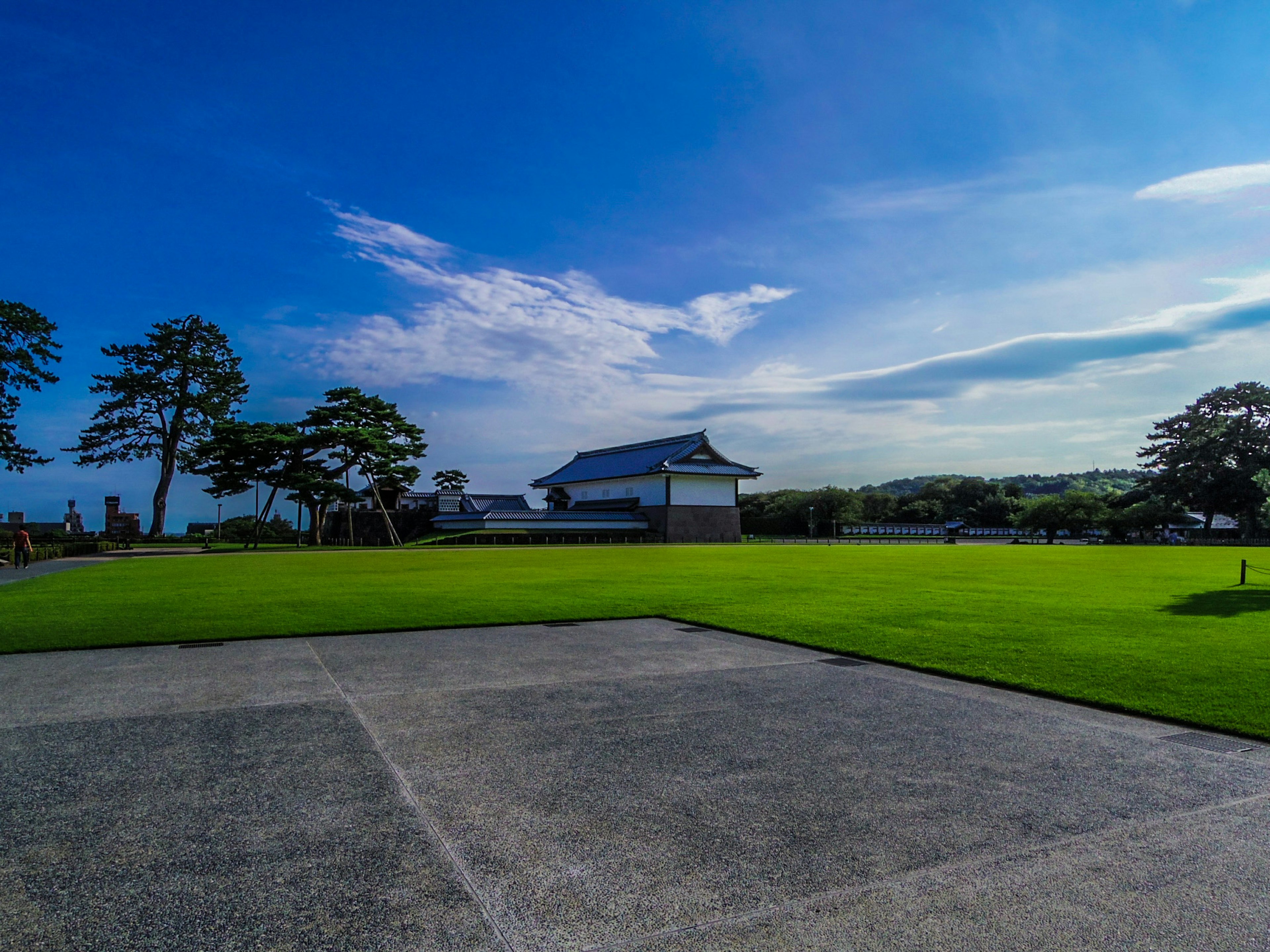 Scenic view of green lawn under a blue sky with a traditional building in the background