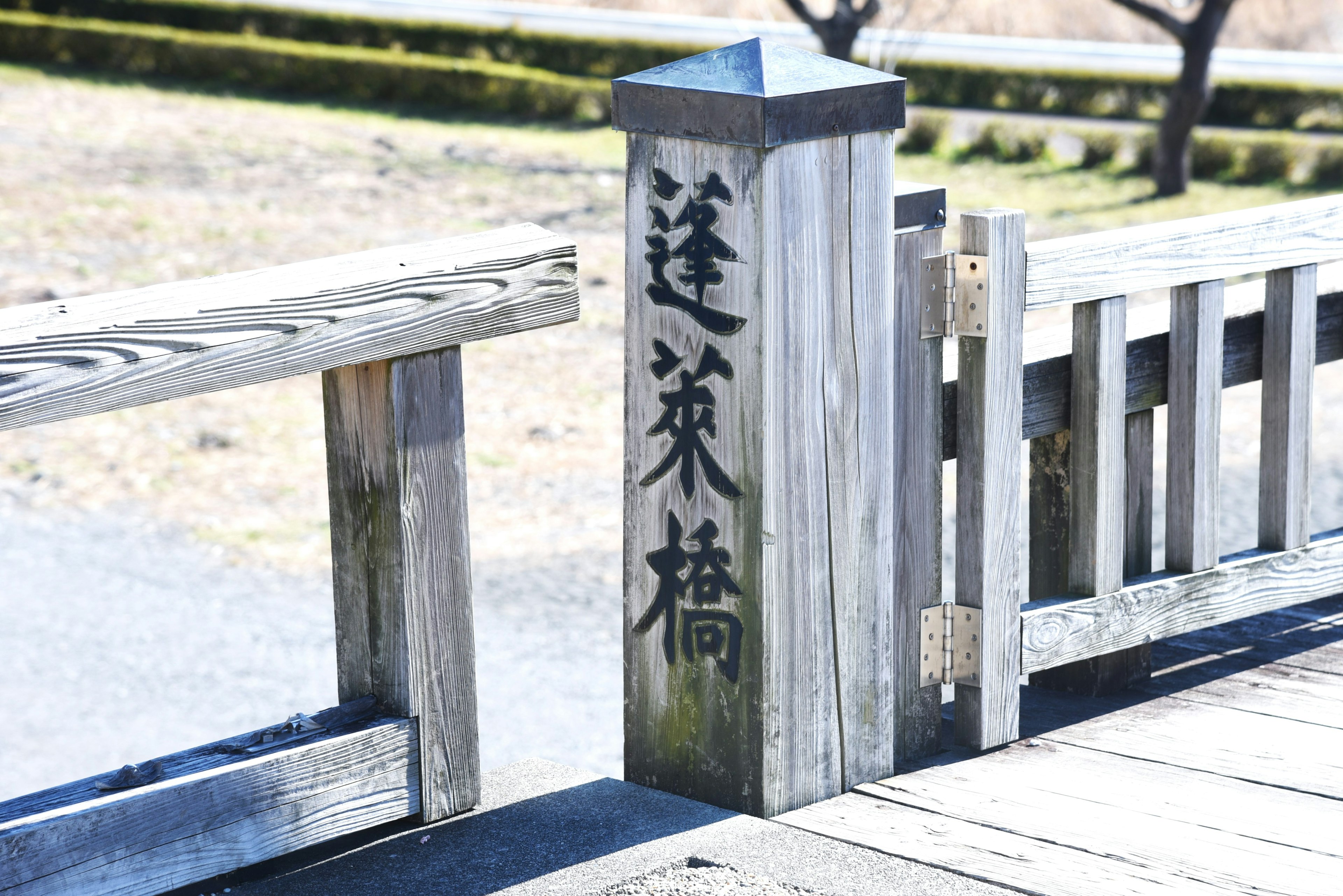 A wooden bridge railing with a decorative pillar featuring Japanese characters