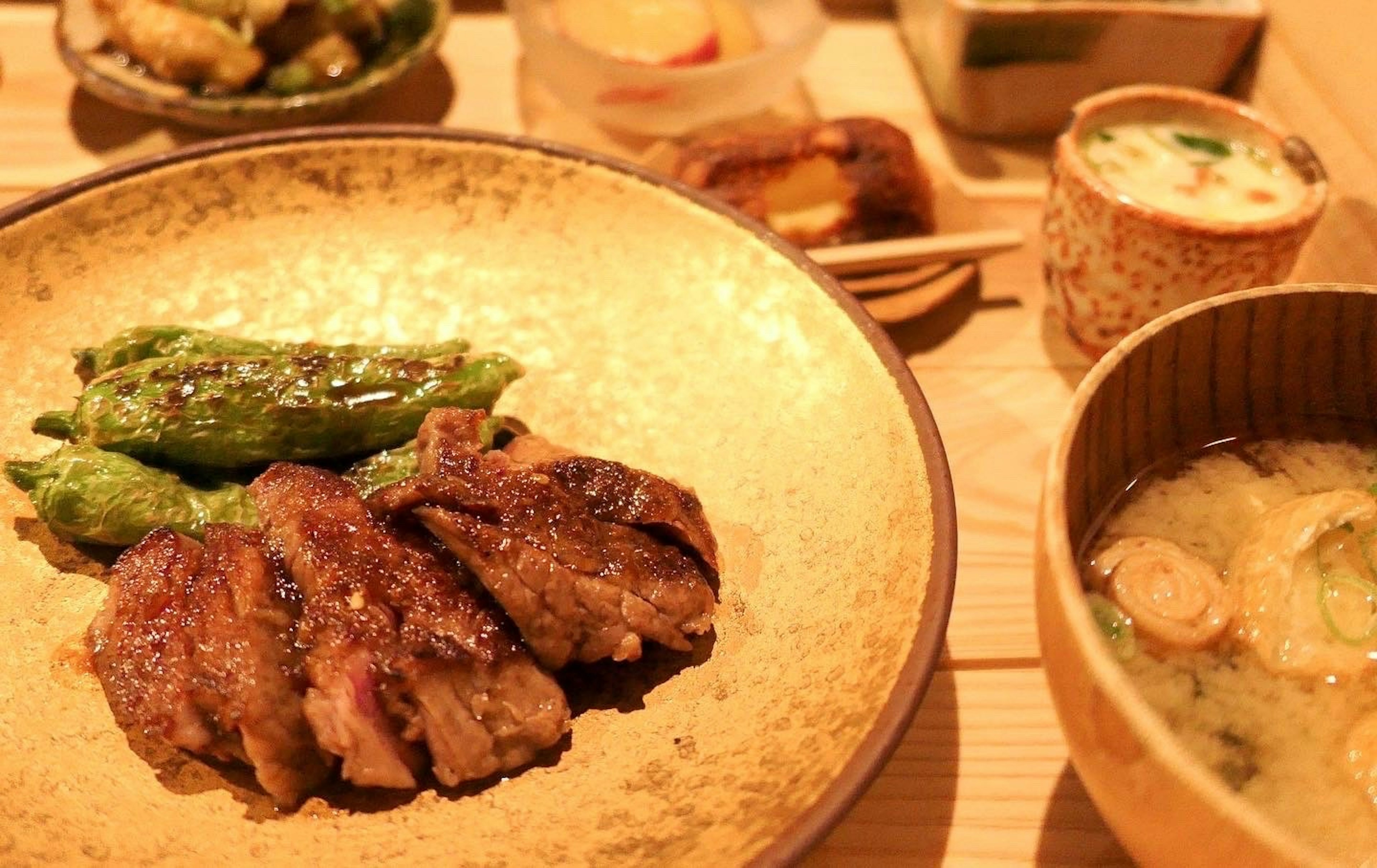 Plato de comida japonesa bellamente presentado con carne a la parrilla, verduras y sopa de miso