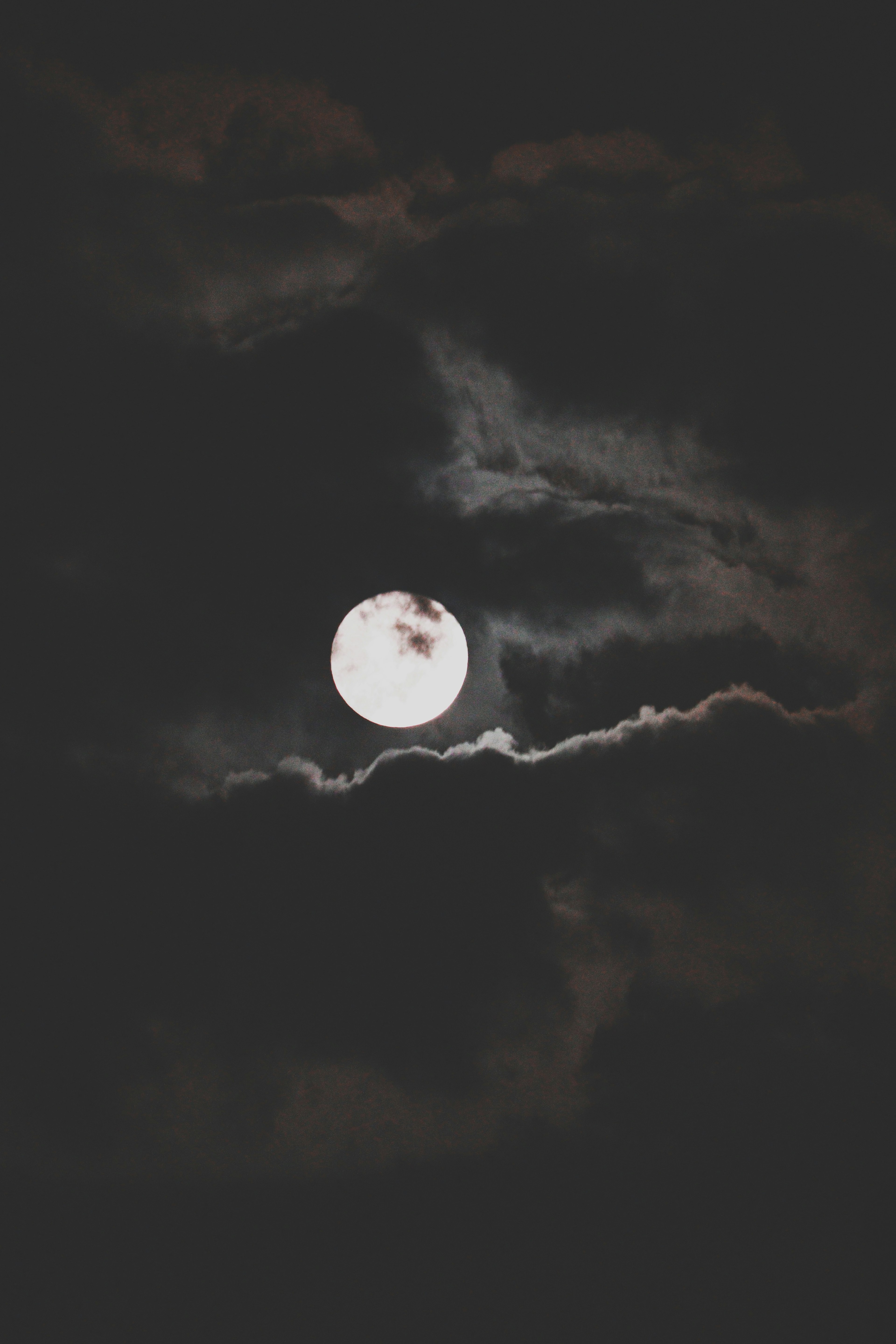 Lune pleine brillante visible à travers des nuages sombres