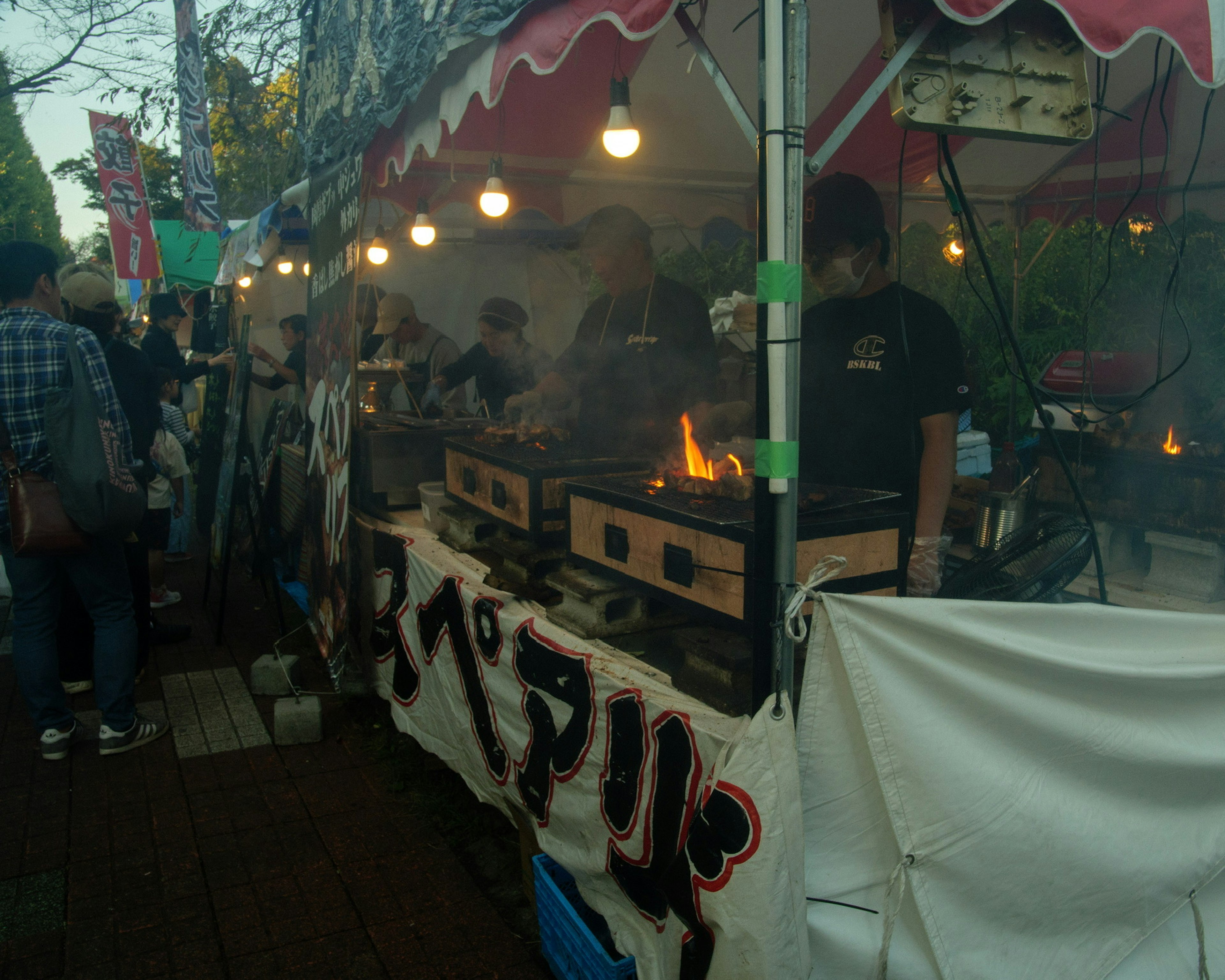 Food vendors cooking at a street stall with smoke rising