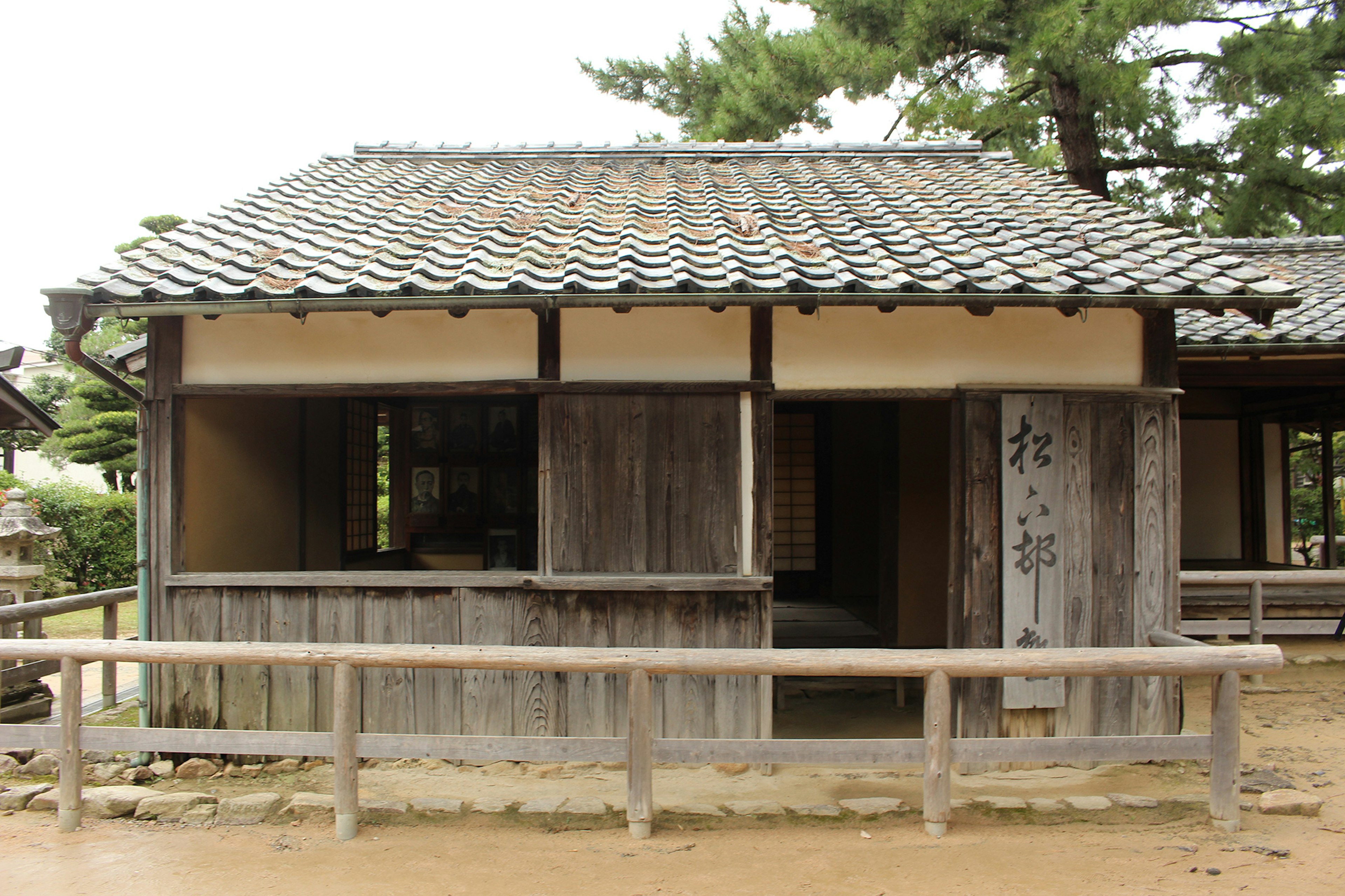 Extérieur d'une vieille maison japonaise en bois avec un toit en tuiles et une rampe en bois