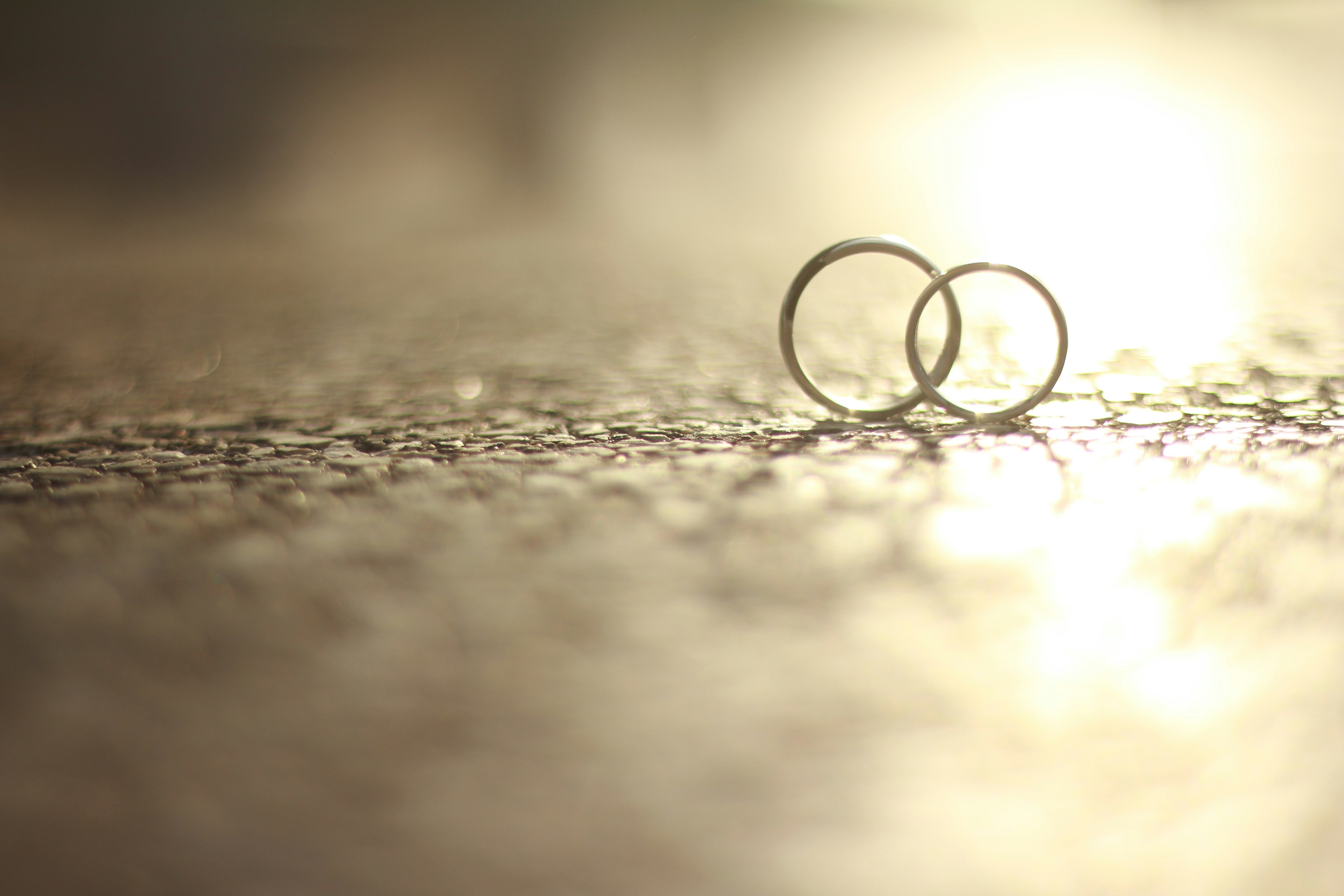 Dos anillos de boda descansando en el suelo iluminados por una luz suave