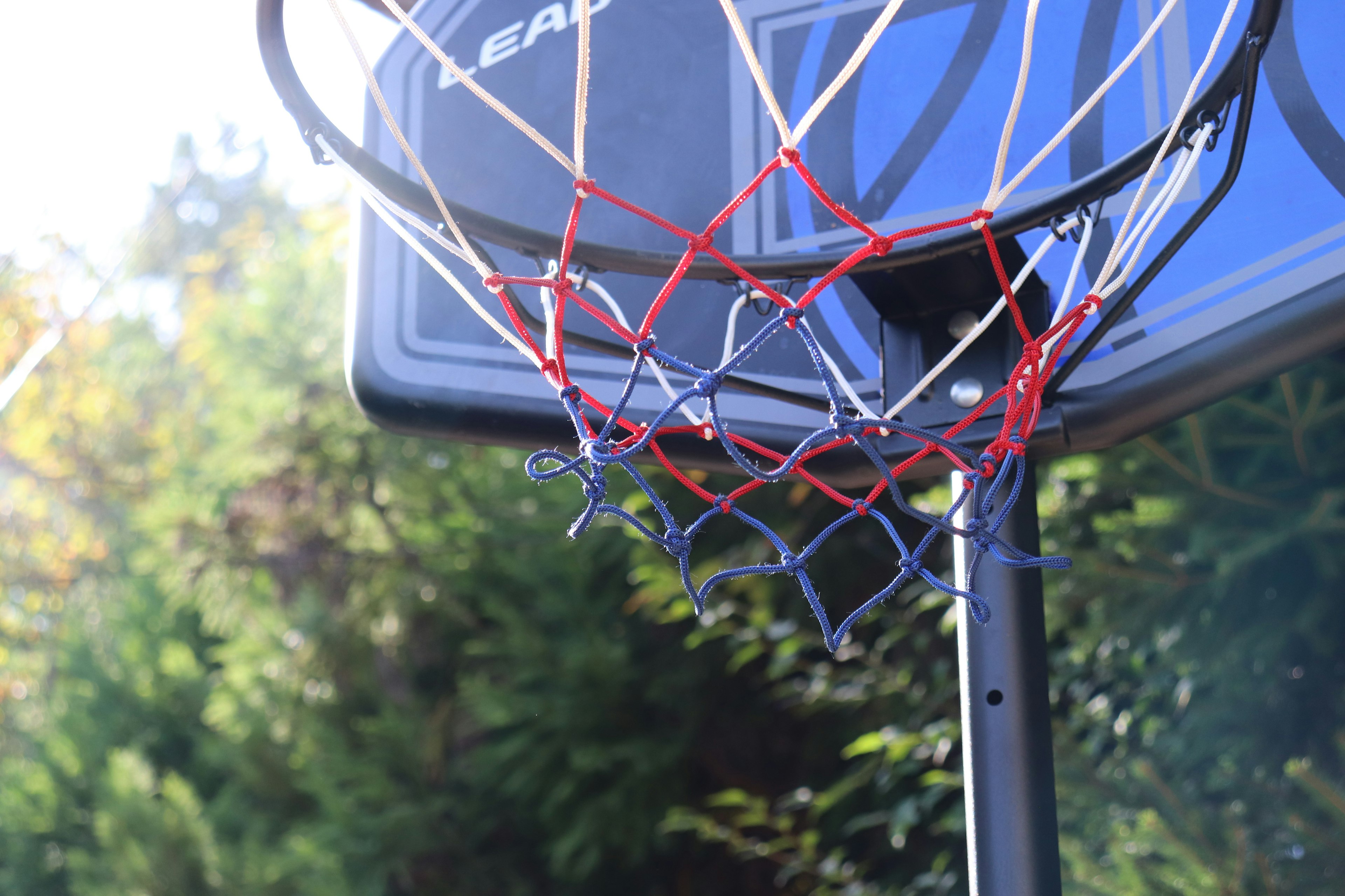 Primer plano de un aro de baloncesto con red roja y azul