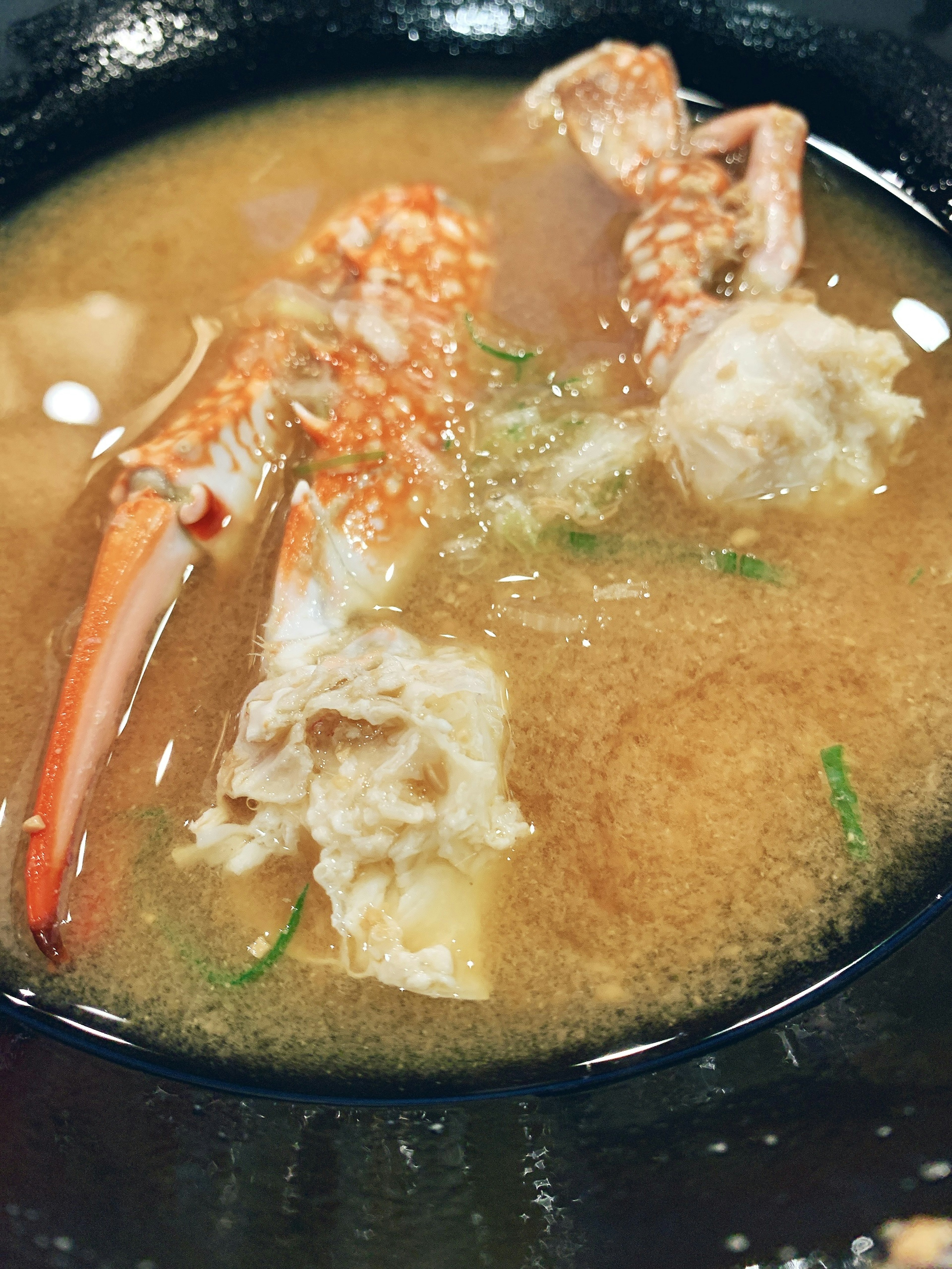 A bowl of soup featuring crab legs and meat