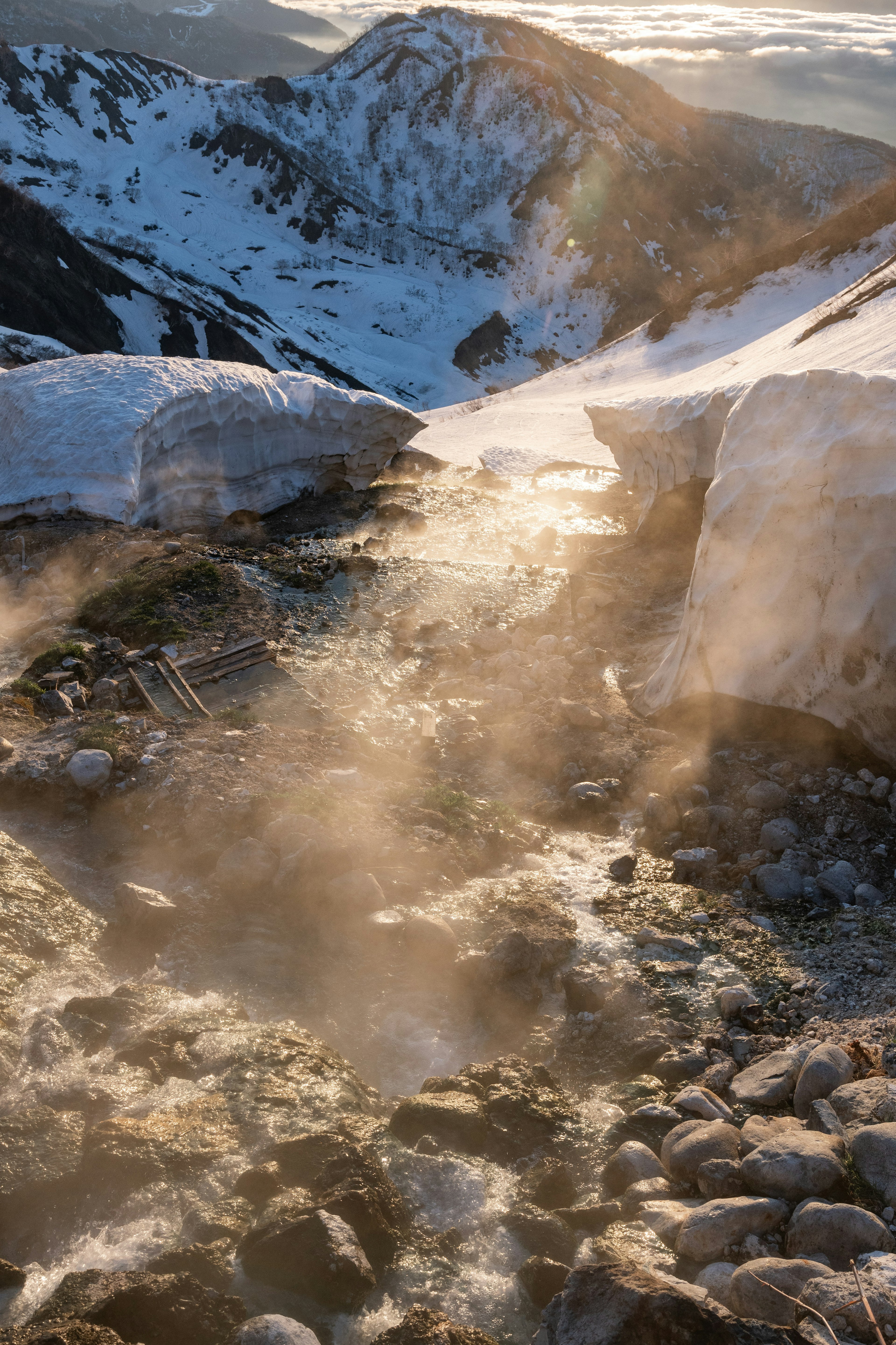 Schneebedeckte Bergkette mit Blick auf einen dampfenden Fluss