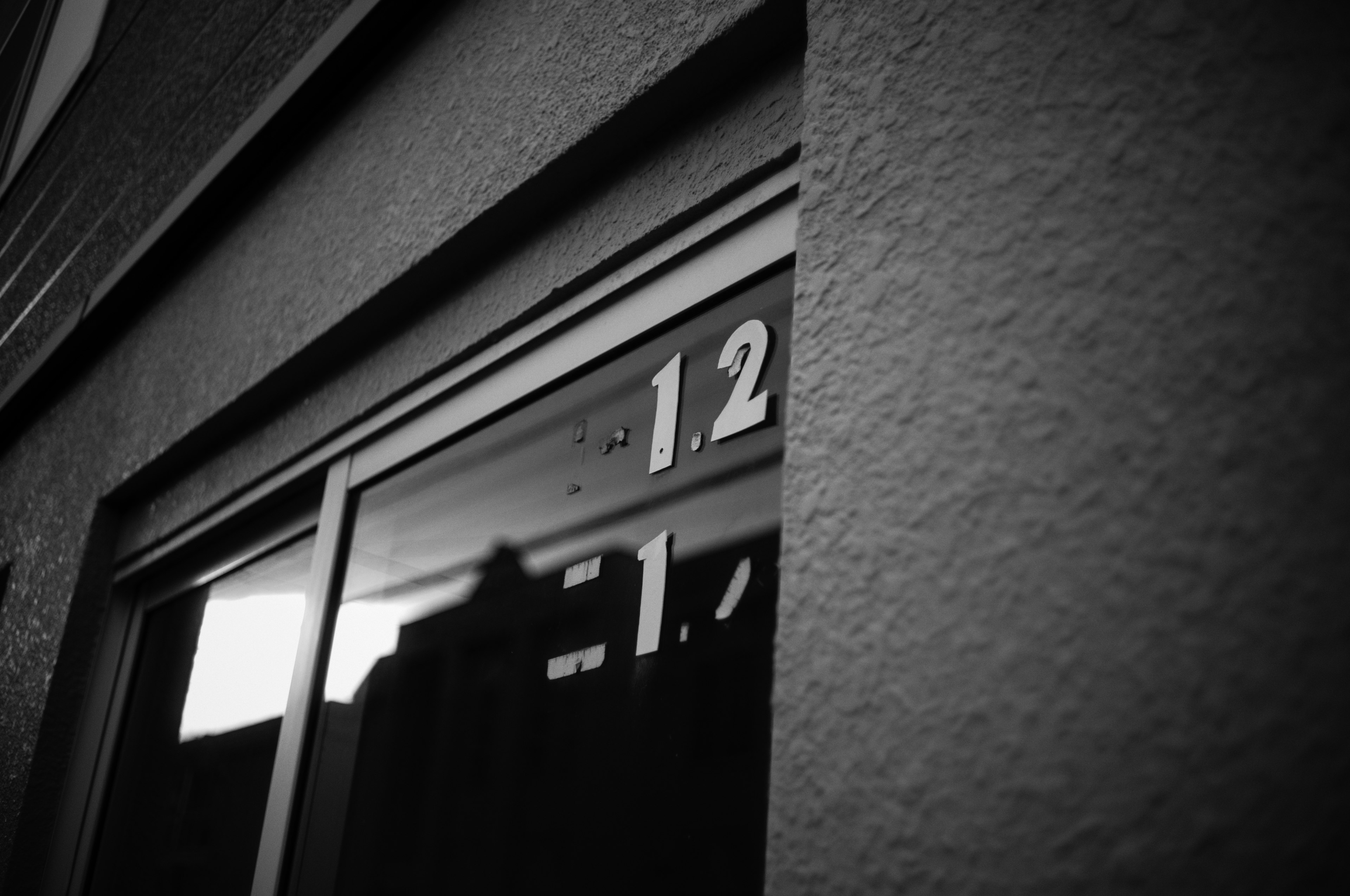 Señal en blanco y negro que muestra el número 12 en la entrada de un edificio