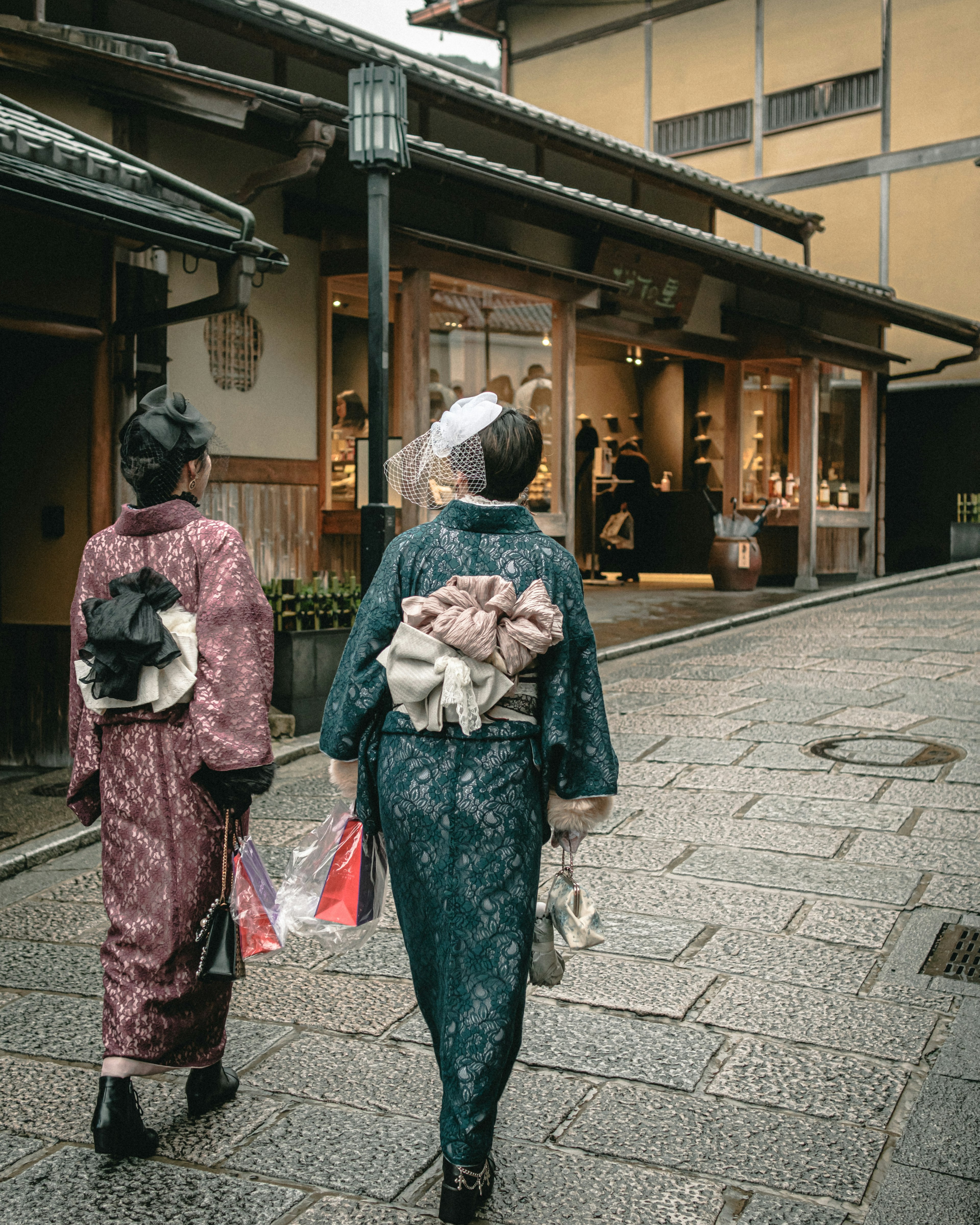 Hai người phụ nữ trong trang phục kimono truyền thống đi trên con đường lát đá