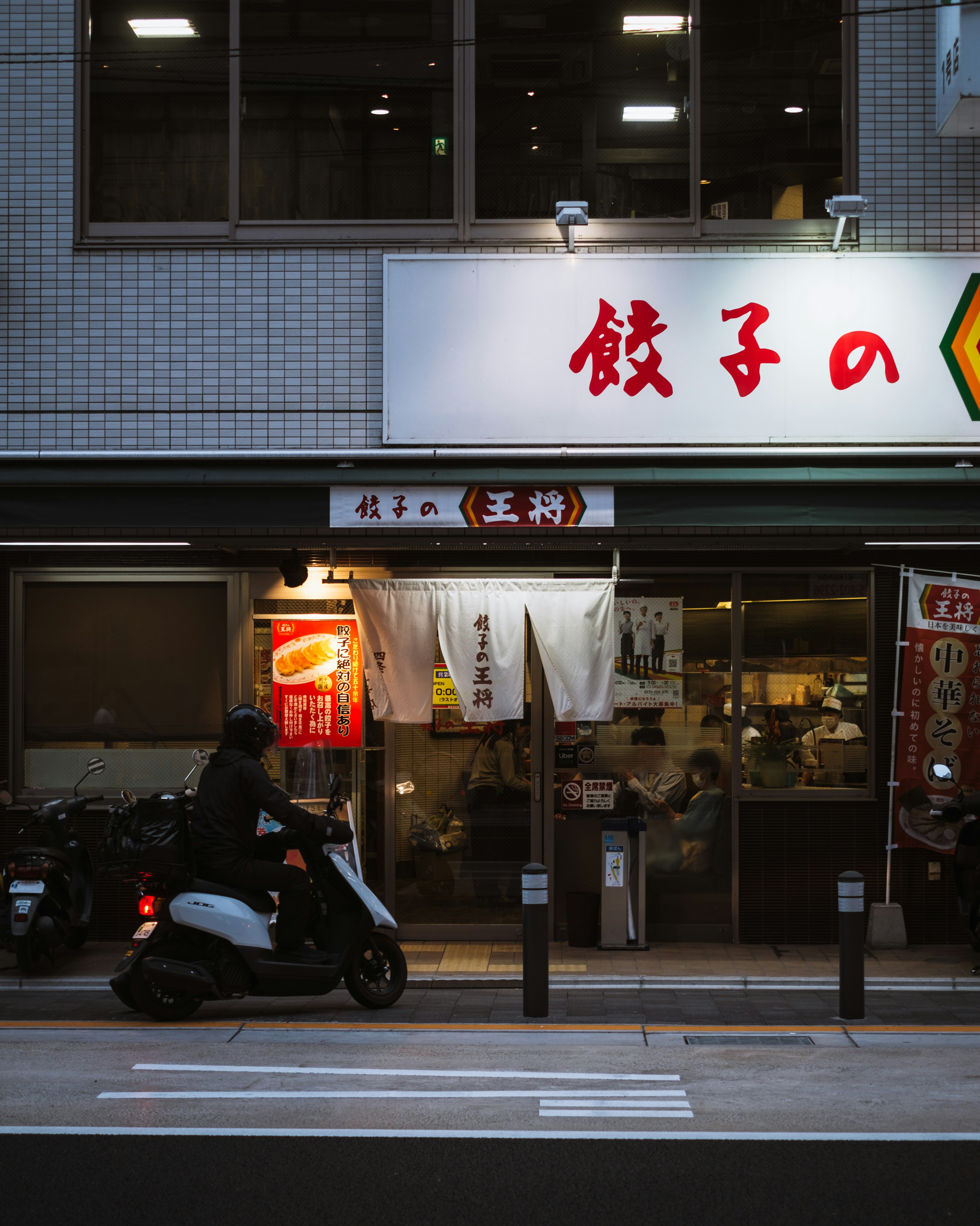 Vista exterior de un restaurante de gyoza con un scooter