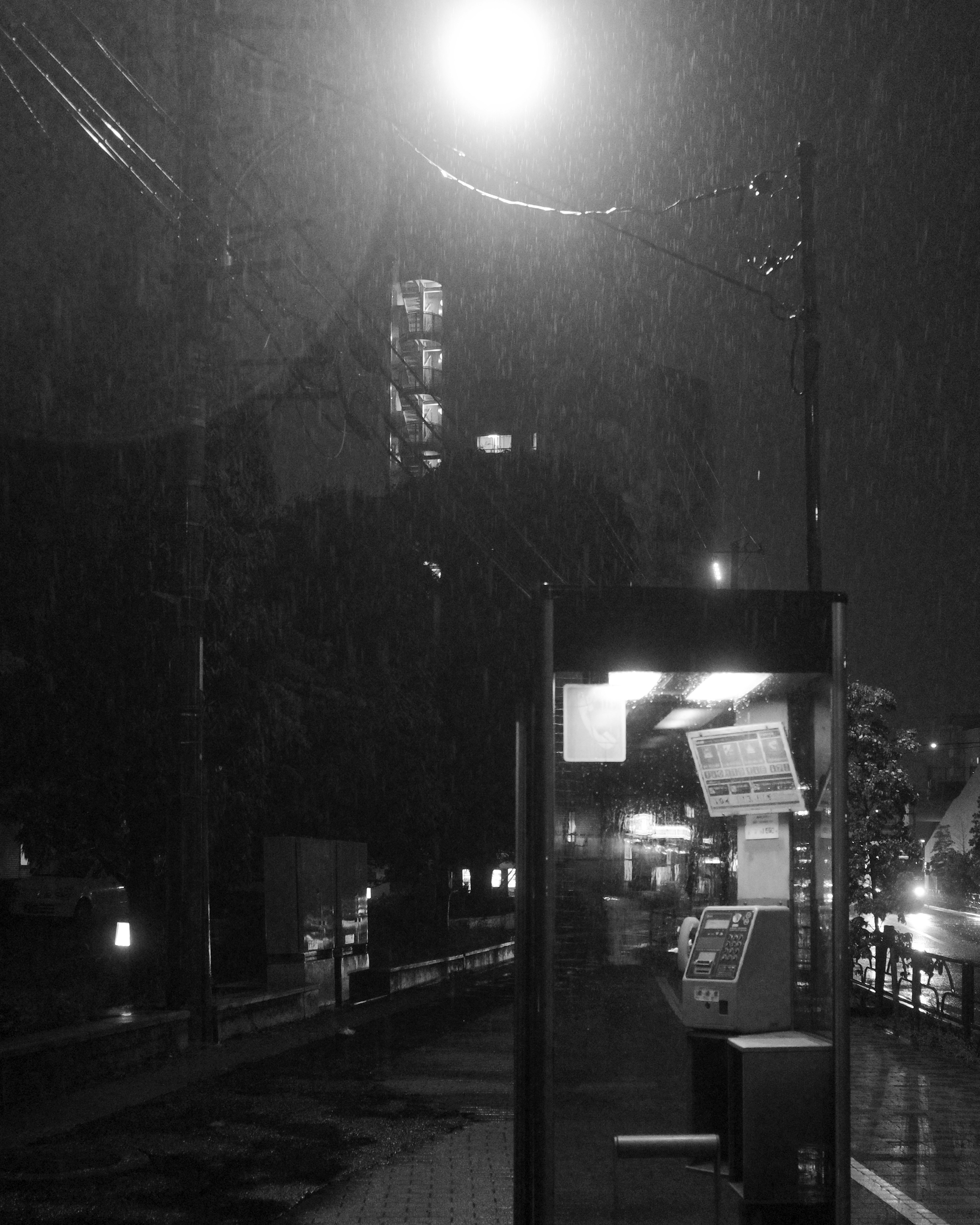 Une cabine téléphonique sous la pluie avec l'éclairage d'un lampadaire