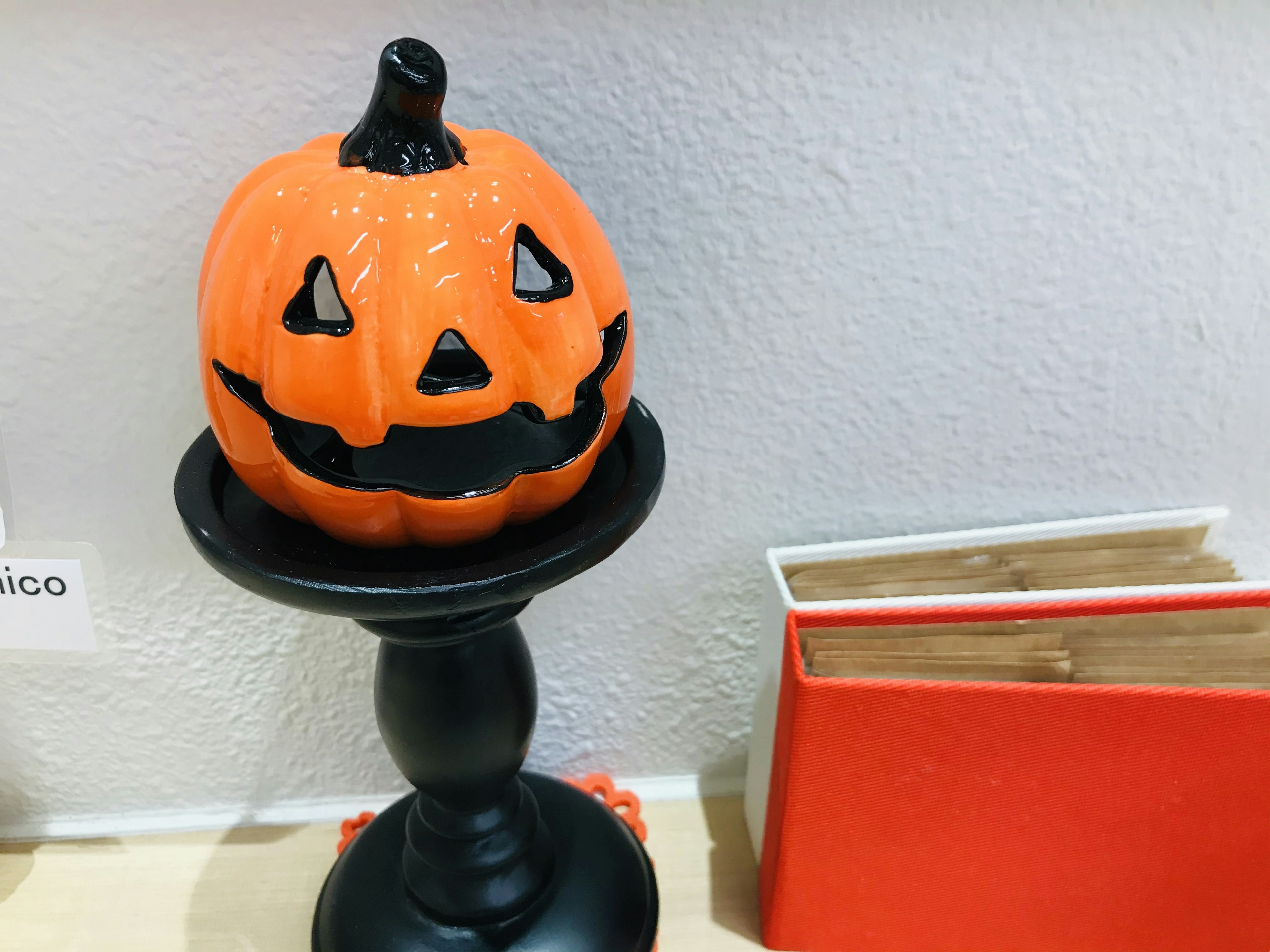 Jack-o'-lantern arancione su un piedistallo nero accanto a libri rossi