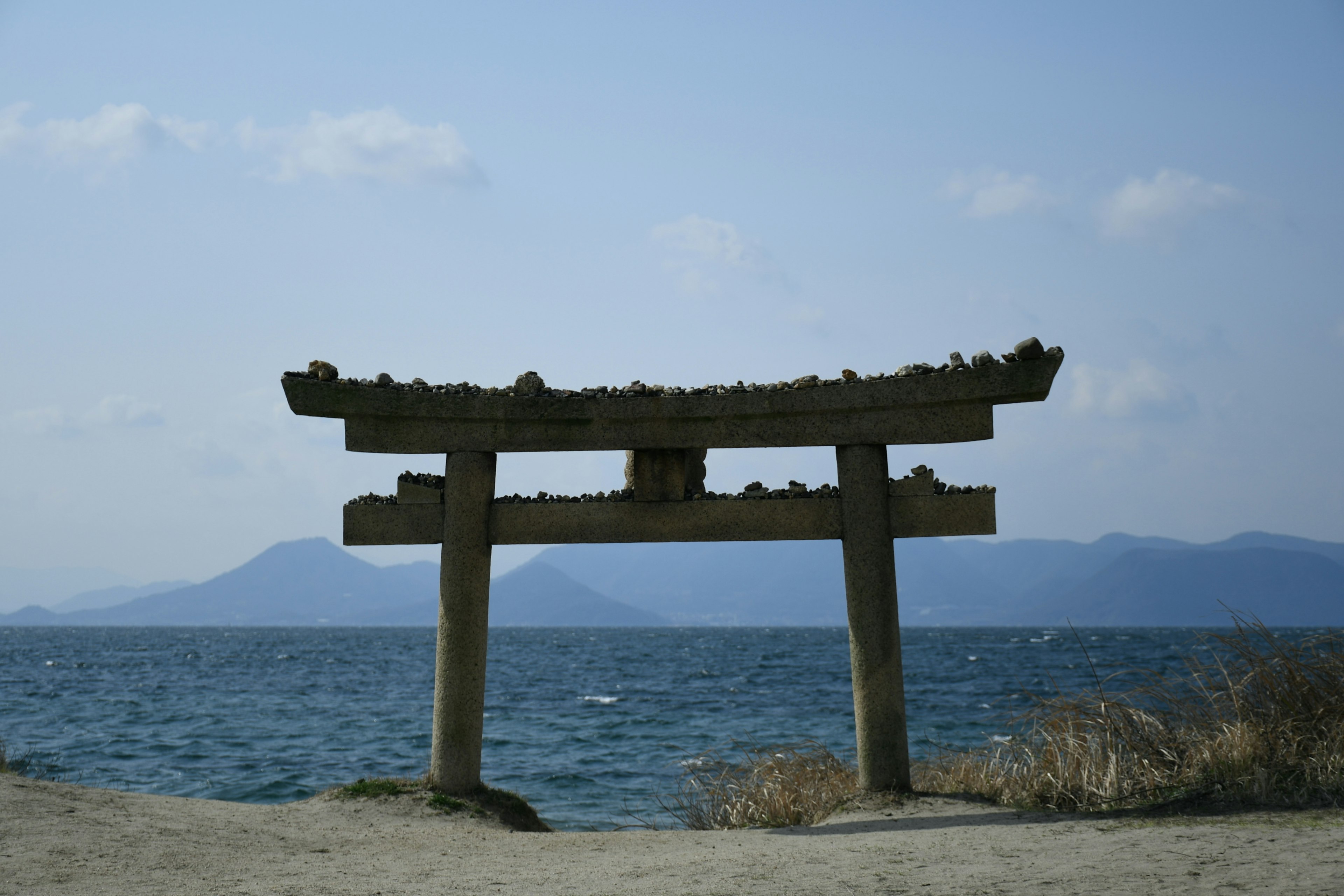 Silhouette d'un torii devant la mer et des montagnes