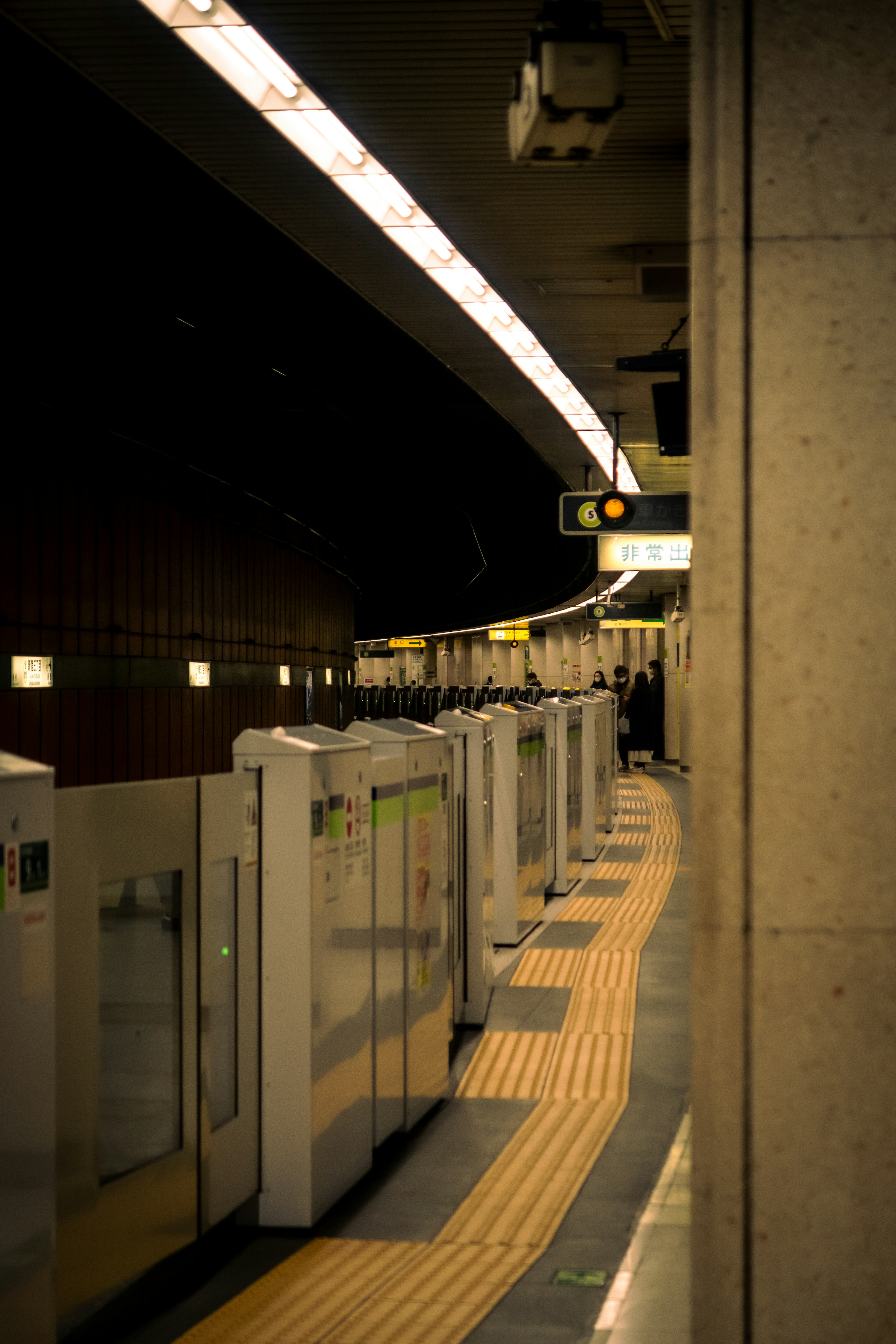 Dark subway station platform with train doors lined up and yellow safety line