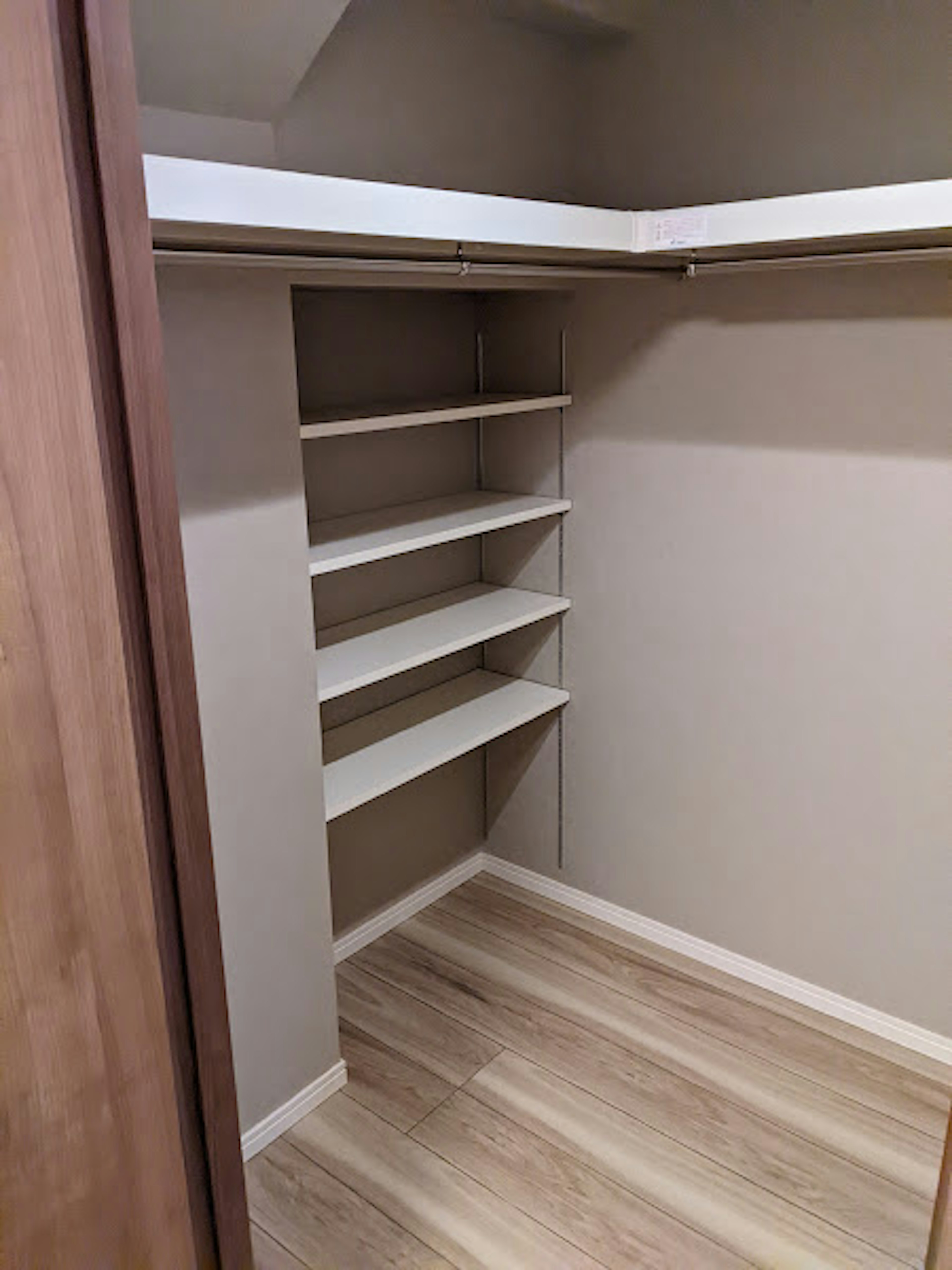 Interior view of an empty closet featuring shelves and wooden flooring