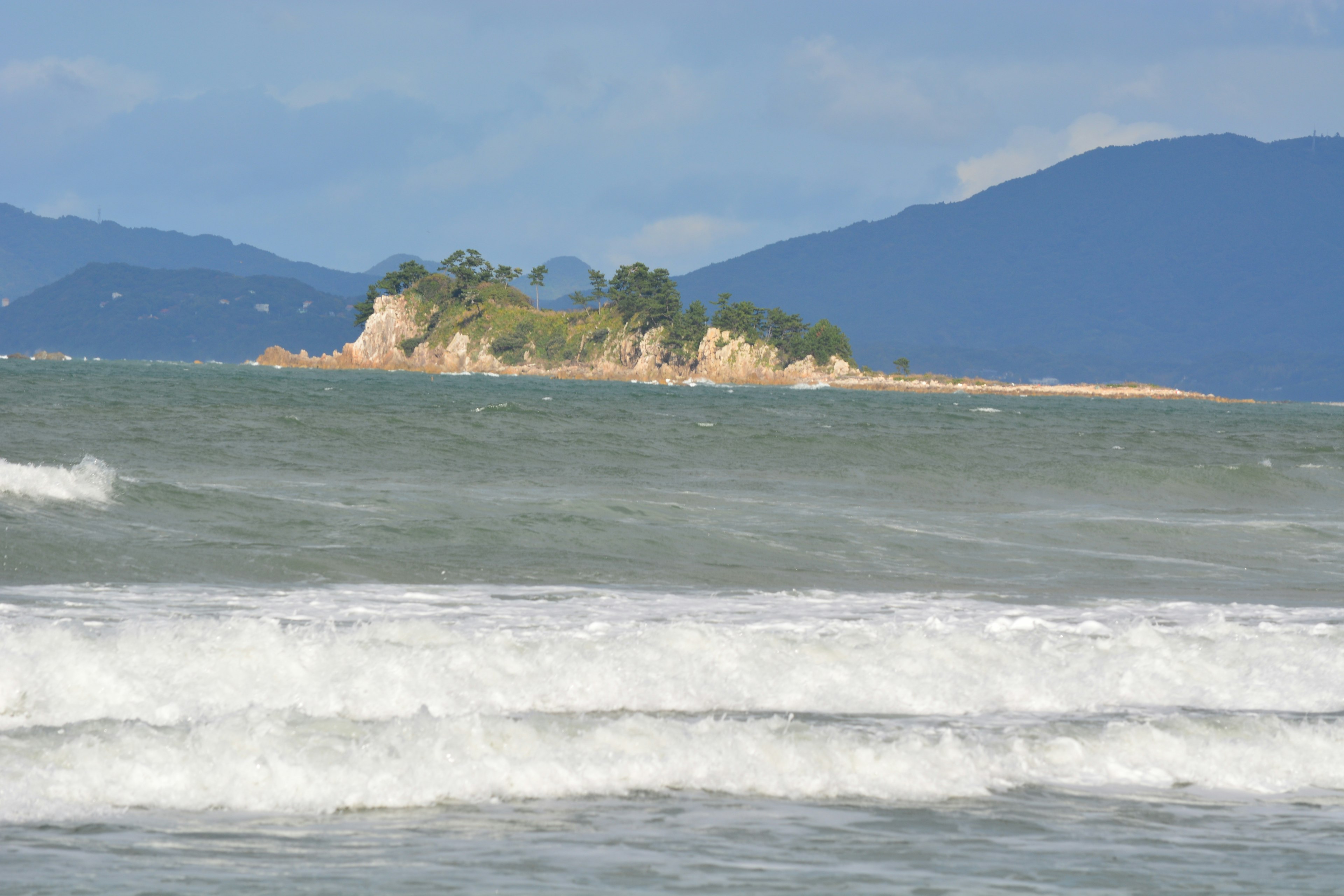 Petite île entourée par une mer bleue et des vagues