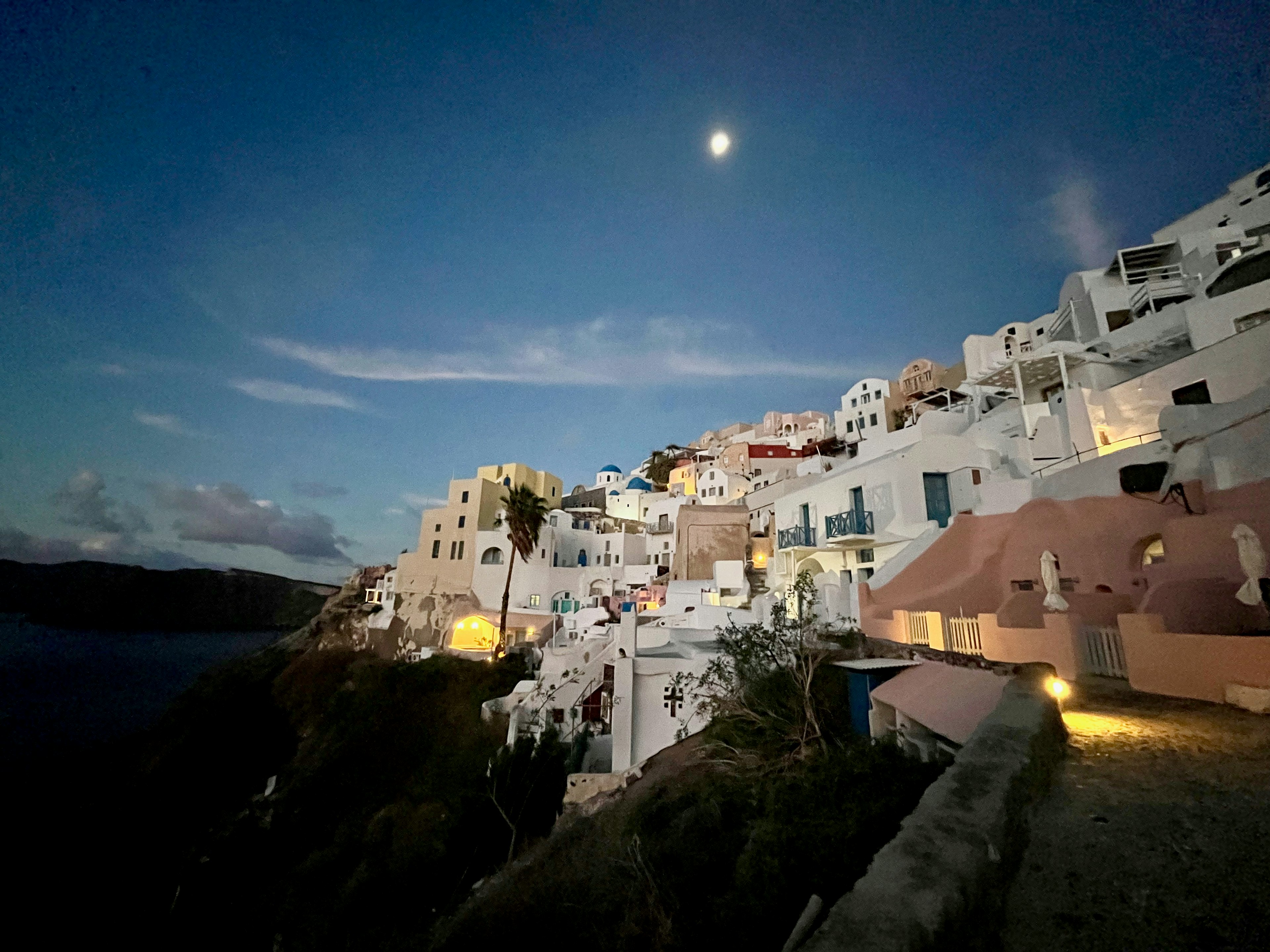 Vue nocturne de Santorin avec des bâtiments blancs et la lune