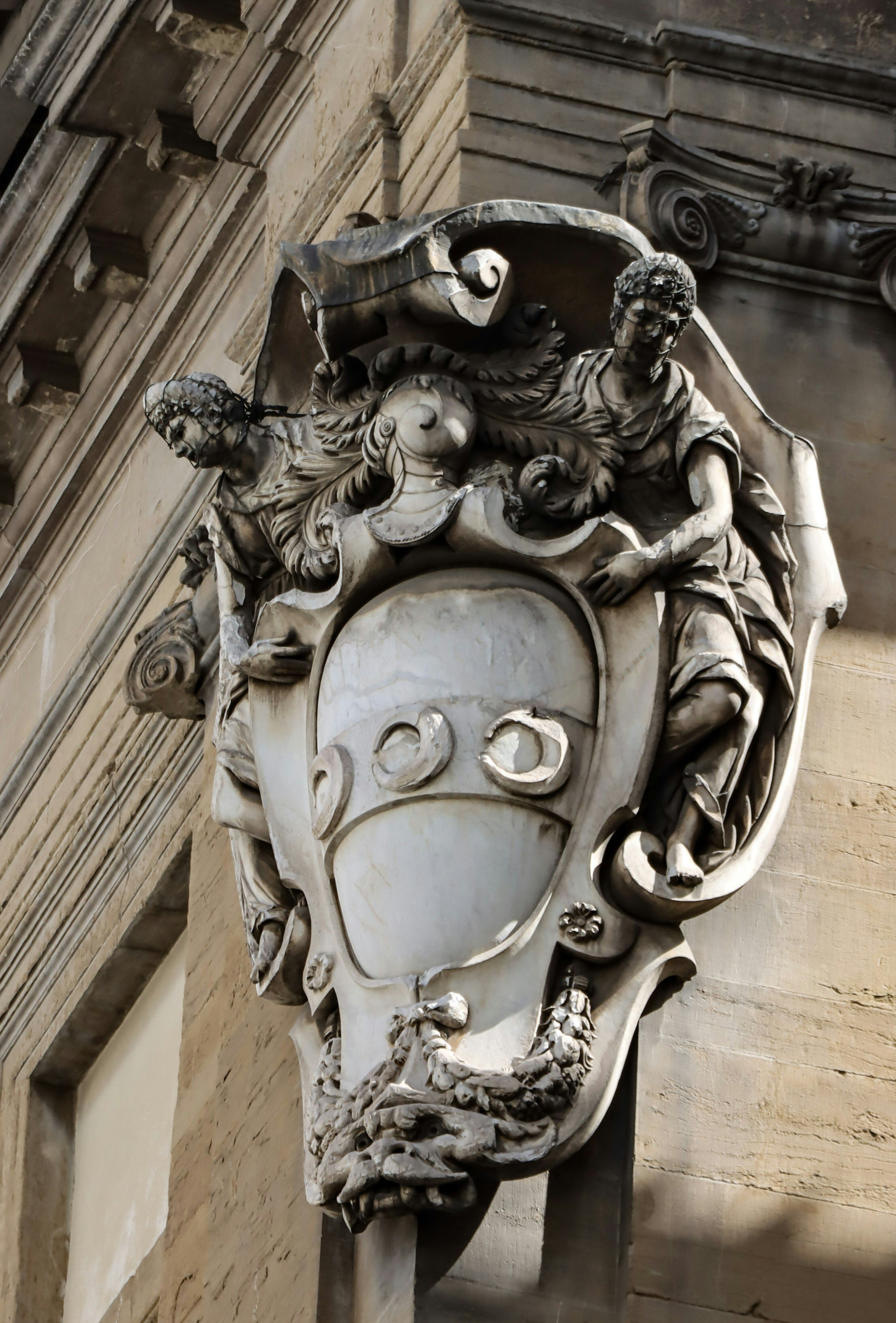 Dekorative Statue mit einem skulptierten Schild, die an der Außenwand eines Gebäudes montiert ist