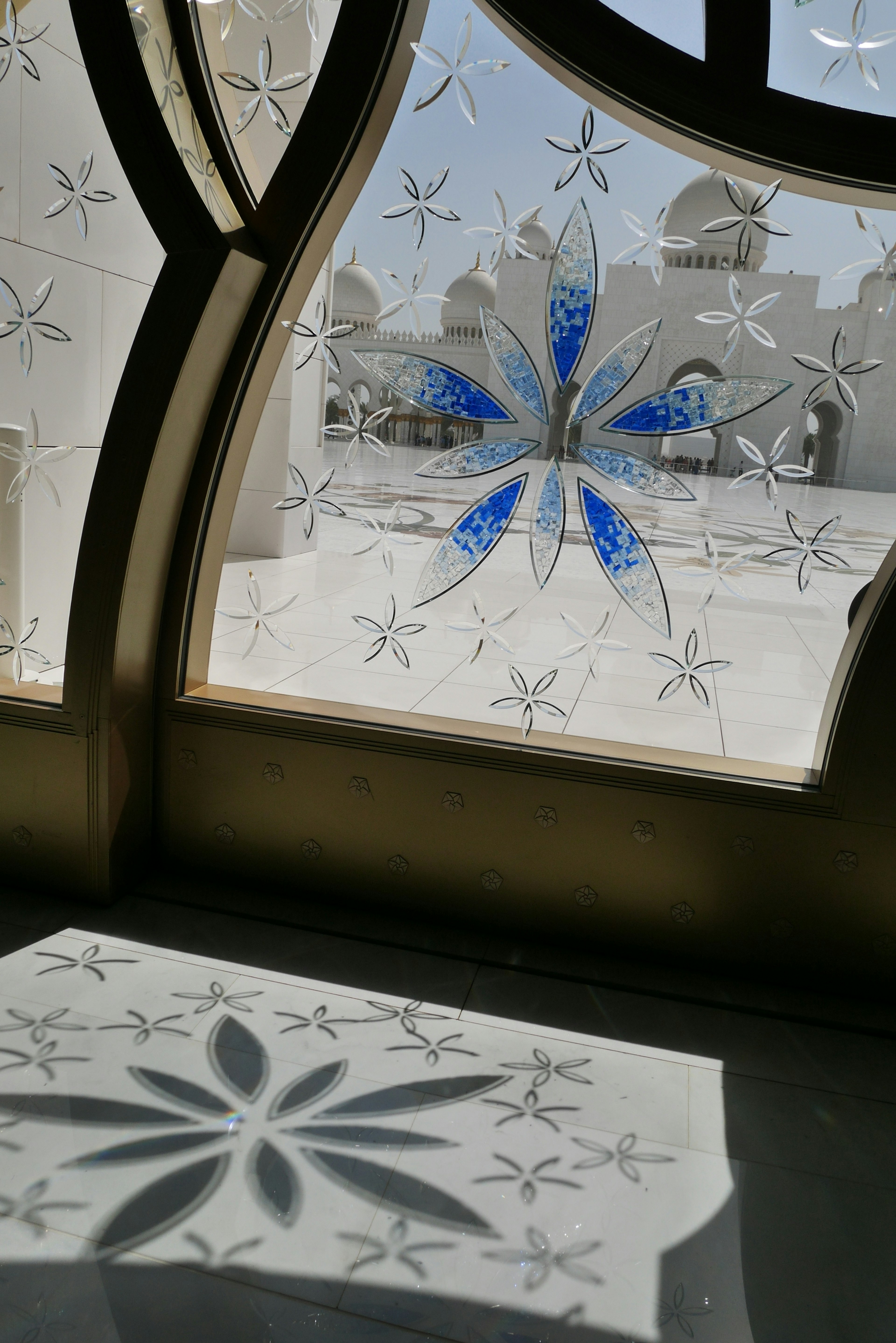 Ventana de vidrio con patrones florales azules y diseños de sombra intrincados