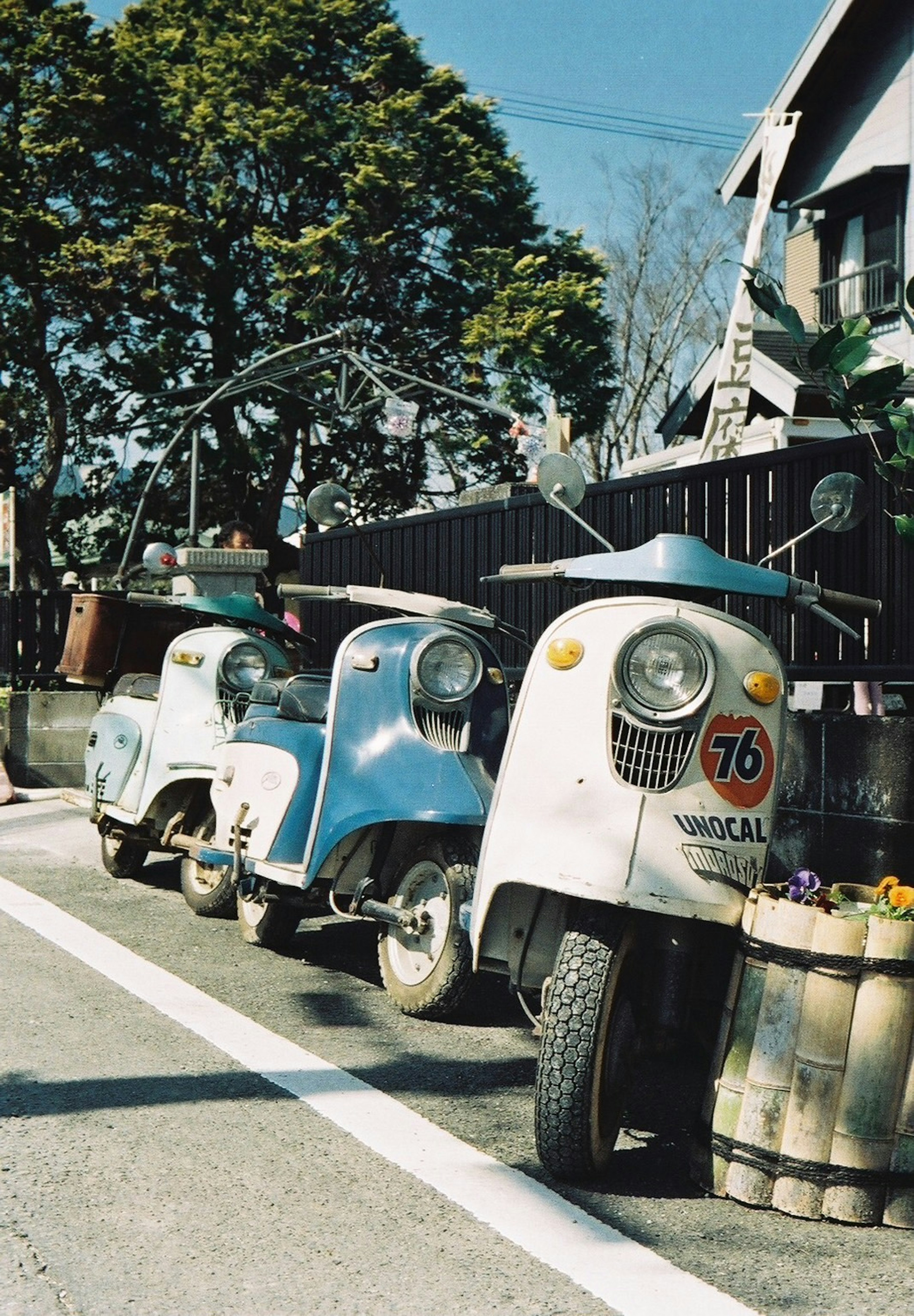 Skuter vintage biru dan putih diparkir di jalan