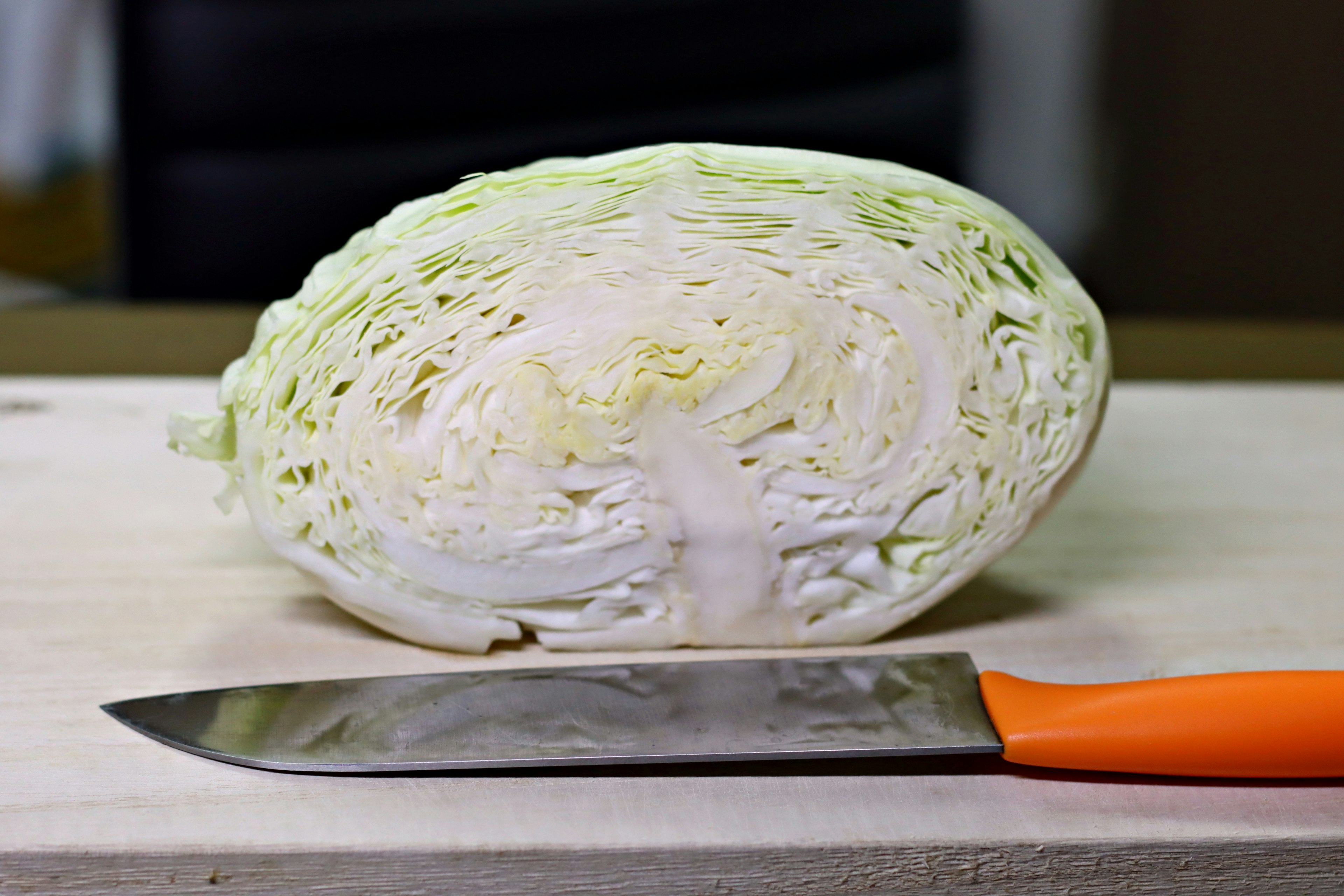 Sliced cabbage on a cutting board with an orange knife