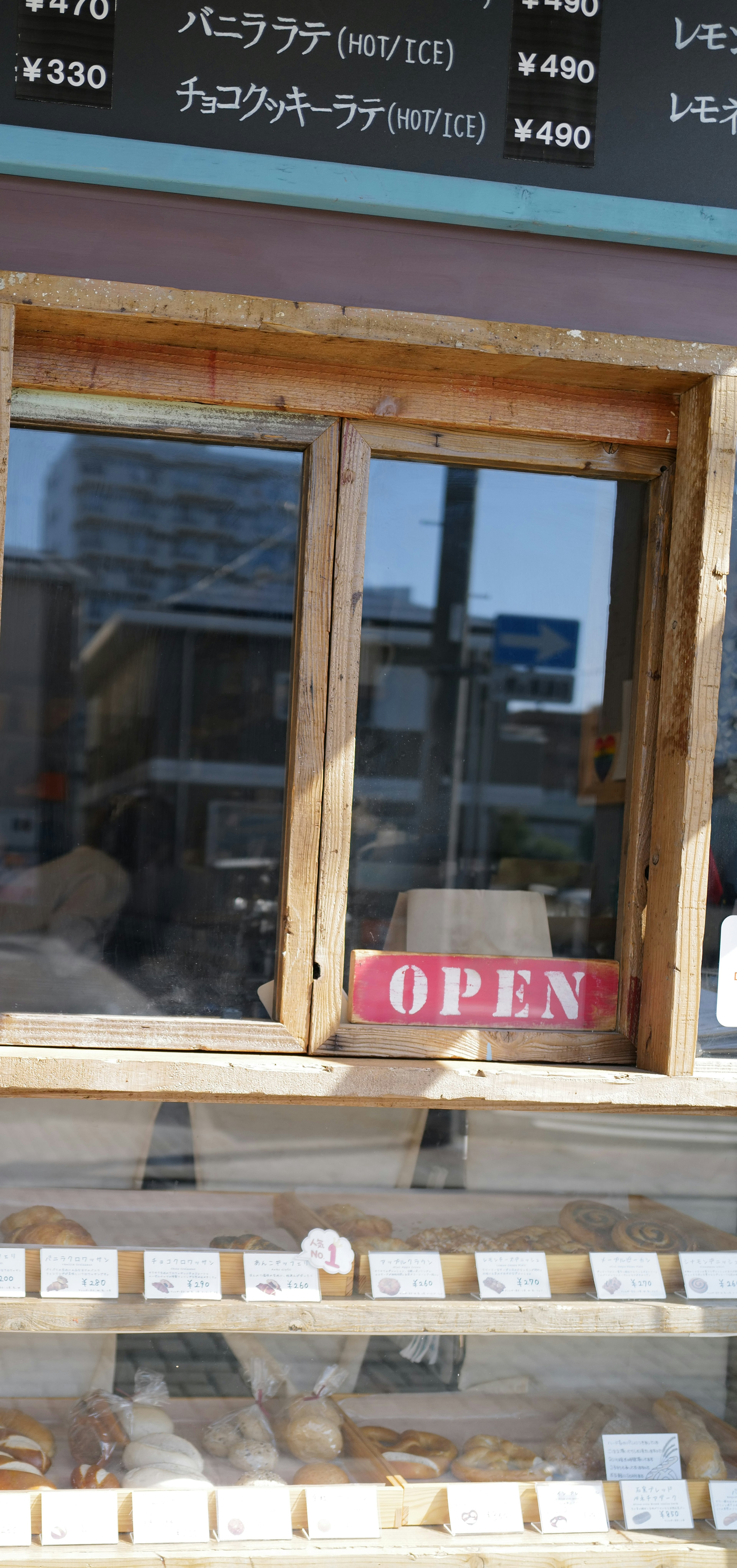 Exterior de una tienda con ventana de madera y un letrero abierto