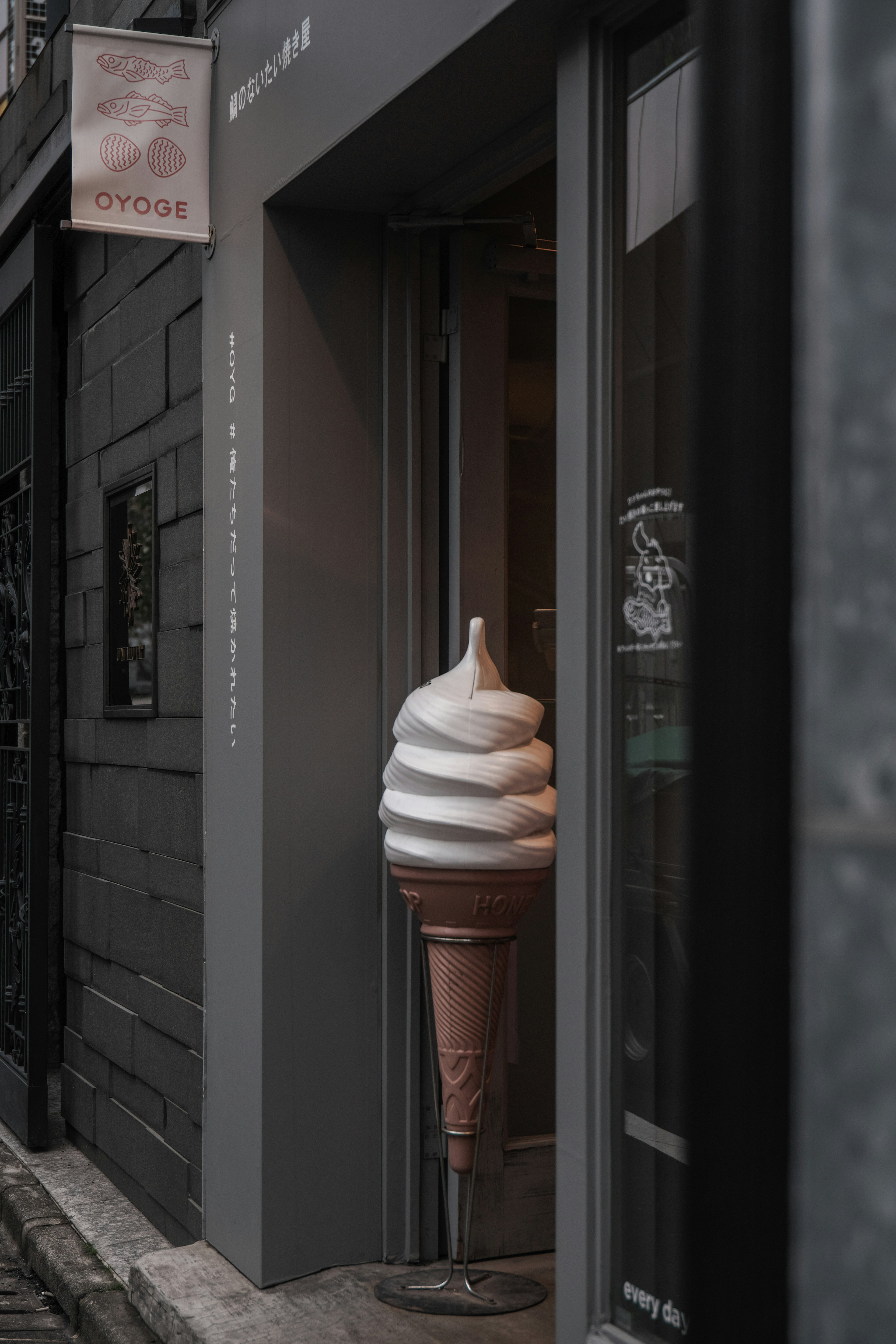 Fachada de tienda con una gran escultura de cono de helado en la entrada