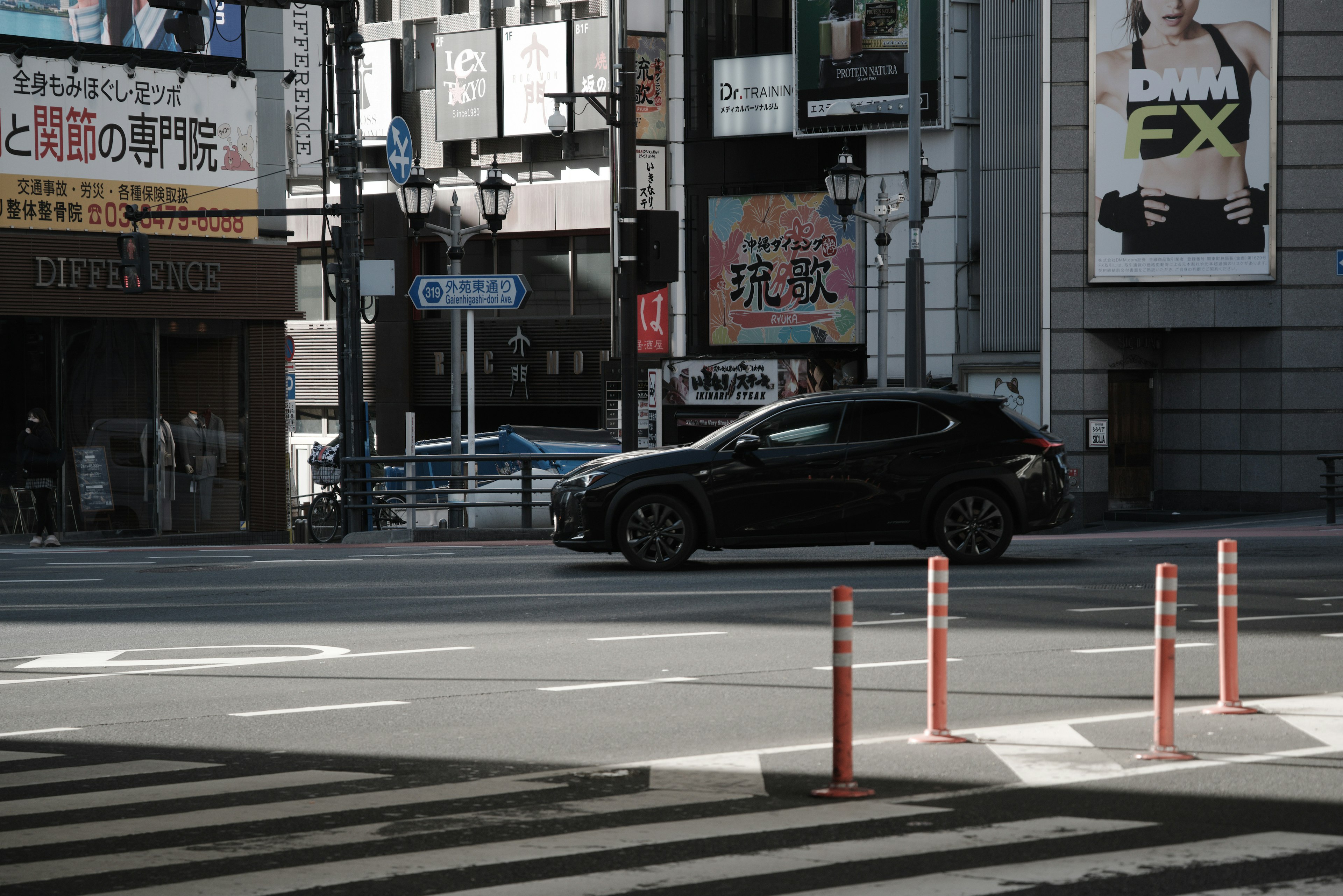 A black car passing through an urban intersection