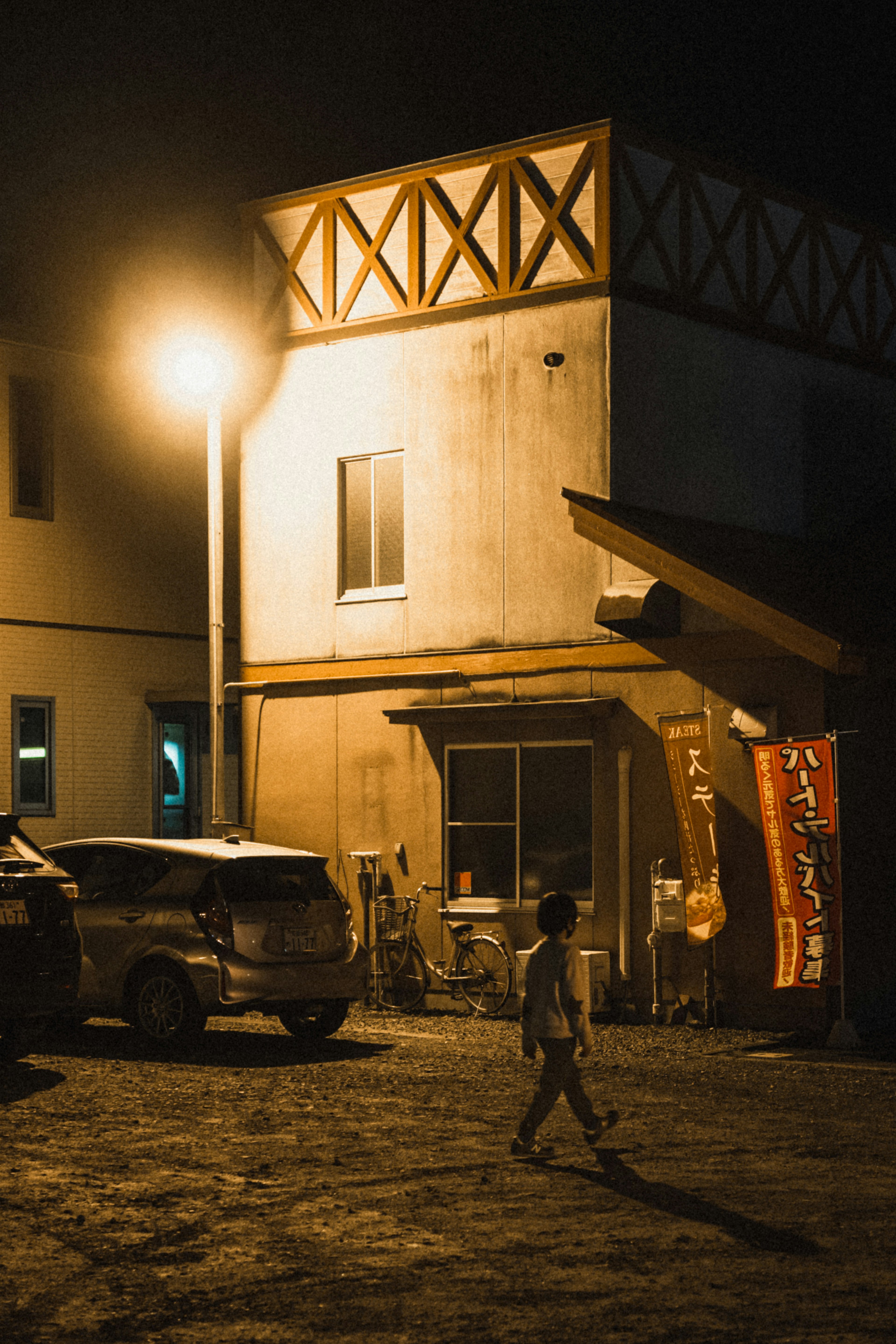 A child walking on the street near a house at night