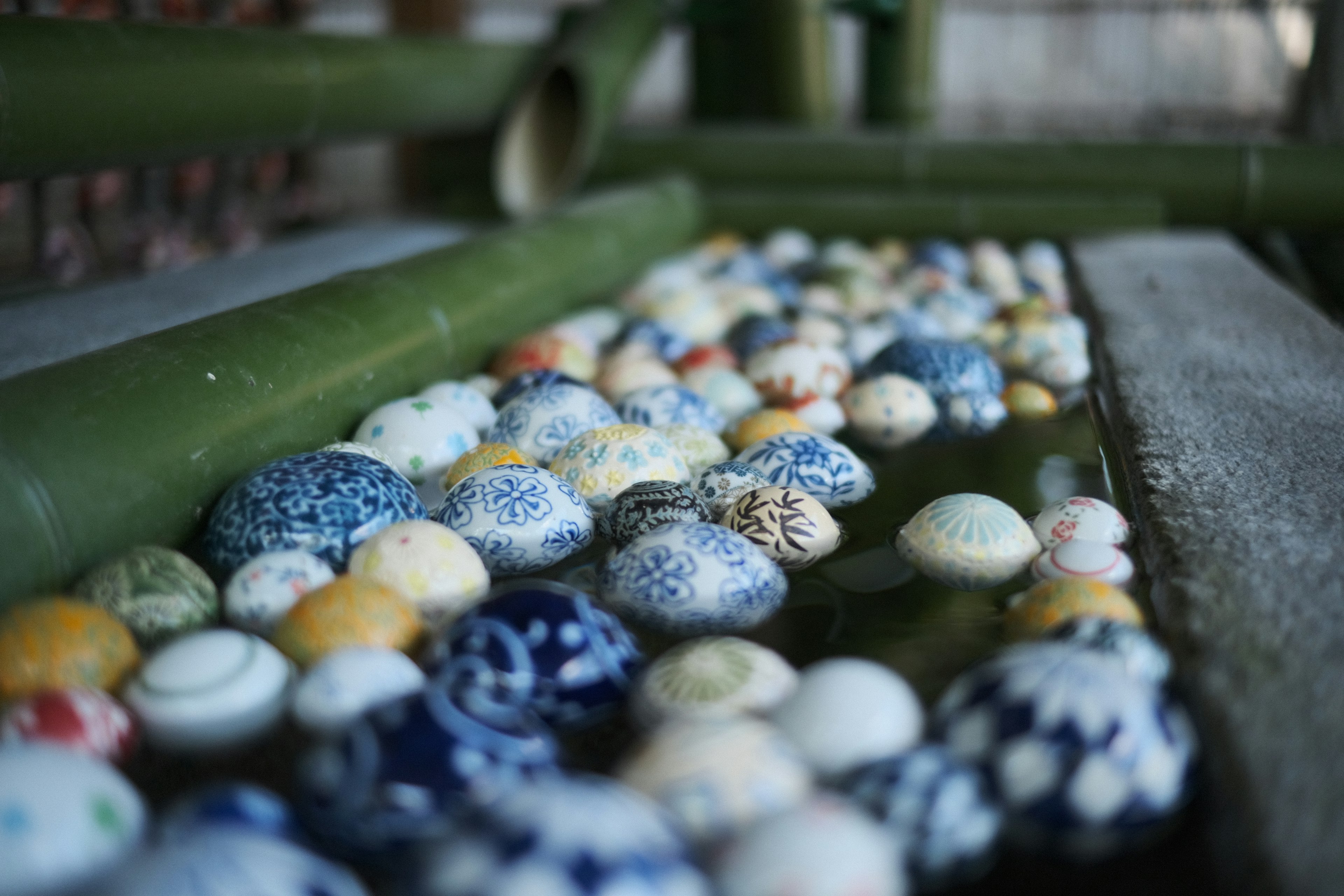 Varias piedras con patrones flotando en el agua entre bambúes