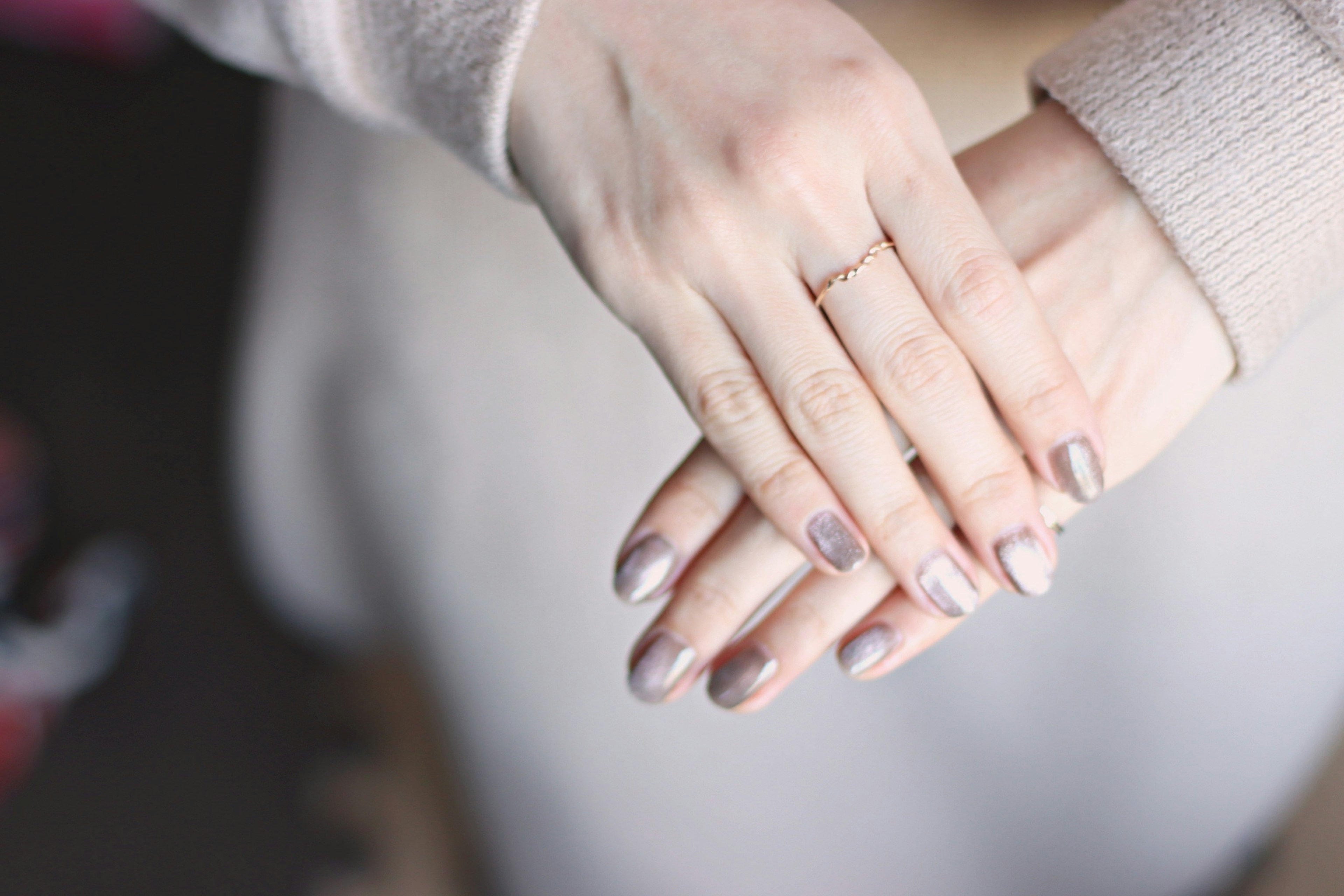 Close-up of a woman's hands clasped together with glossy gray nails