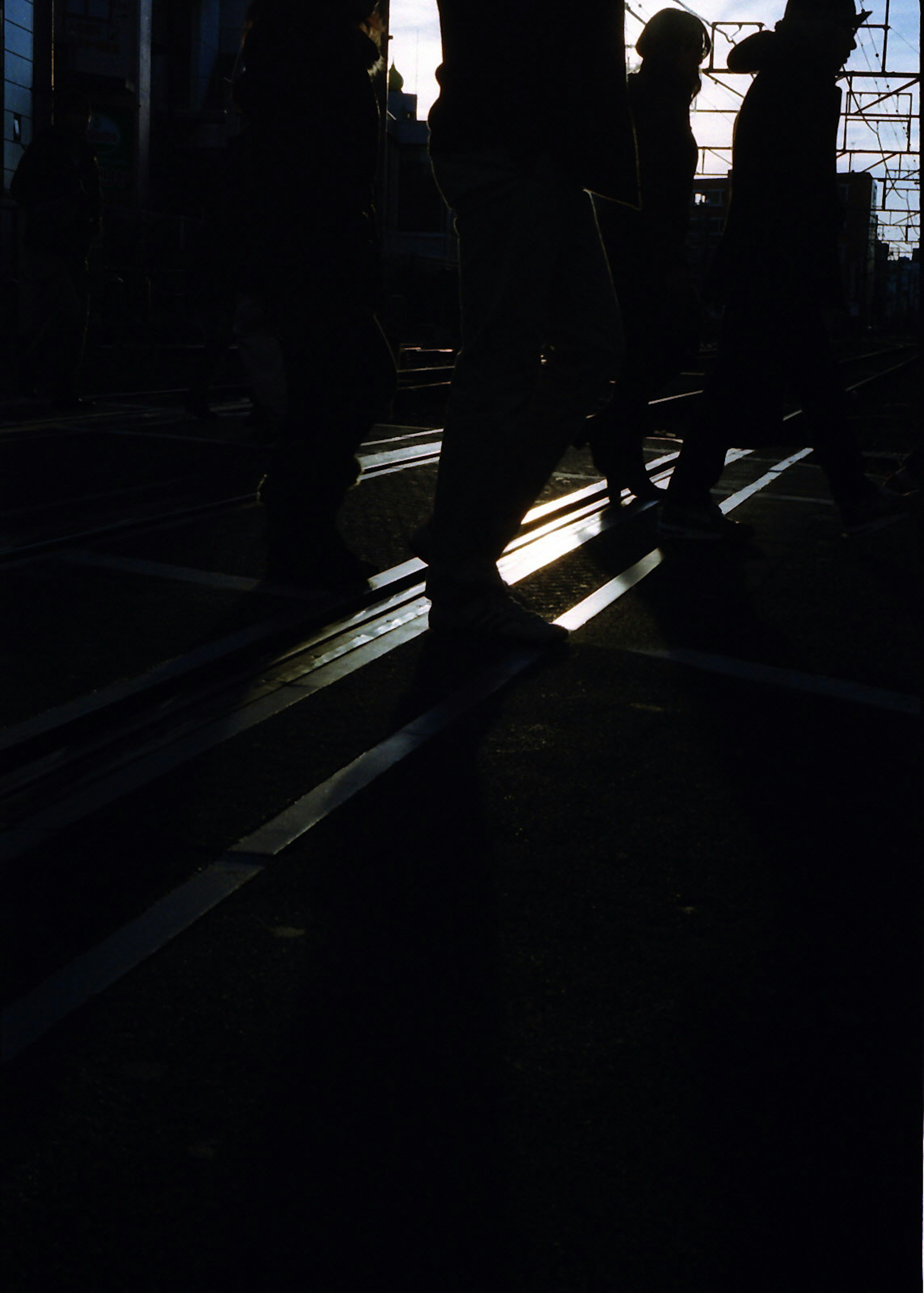 Siluetas de personas caminando en una ciudad con sombras cruzadas