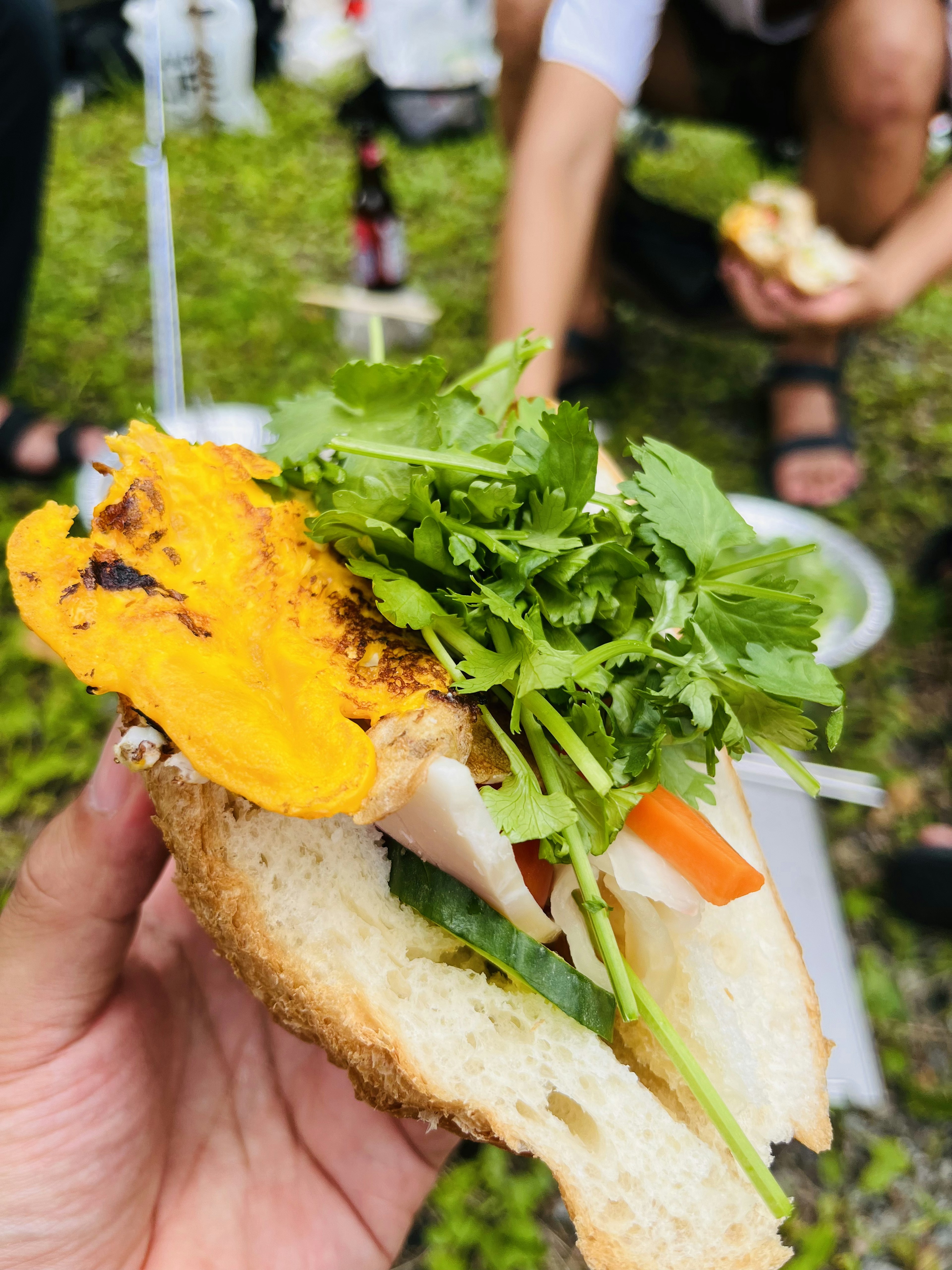 Una mano che tiene un panino guarnito con verdure fresche e erbe