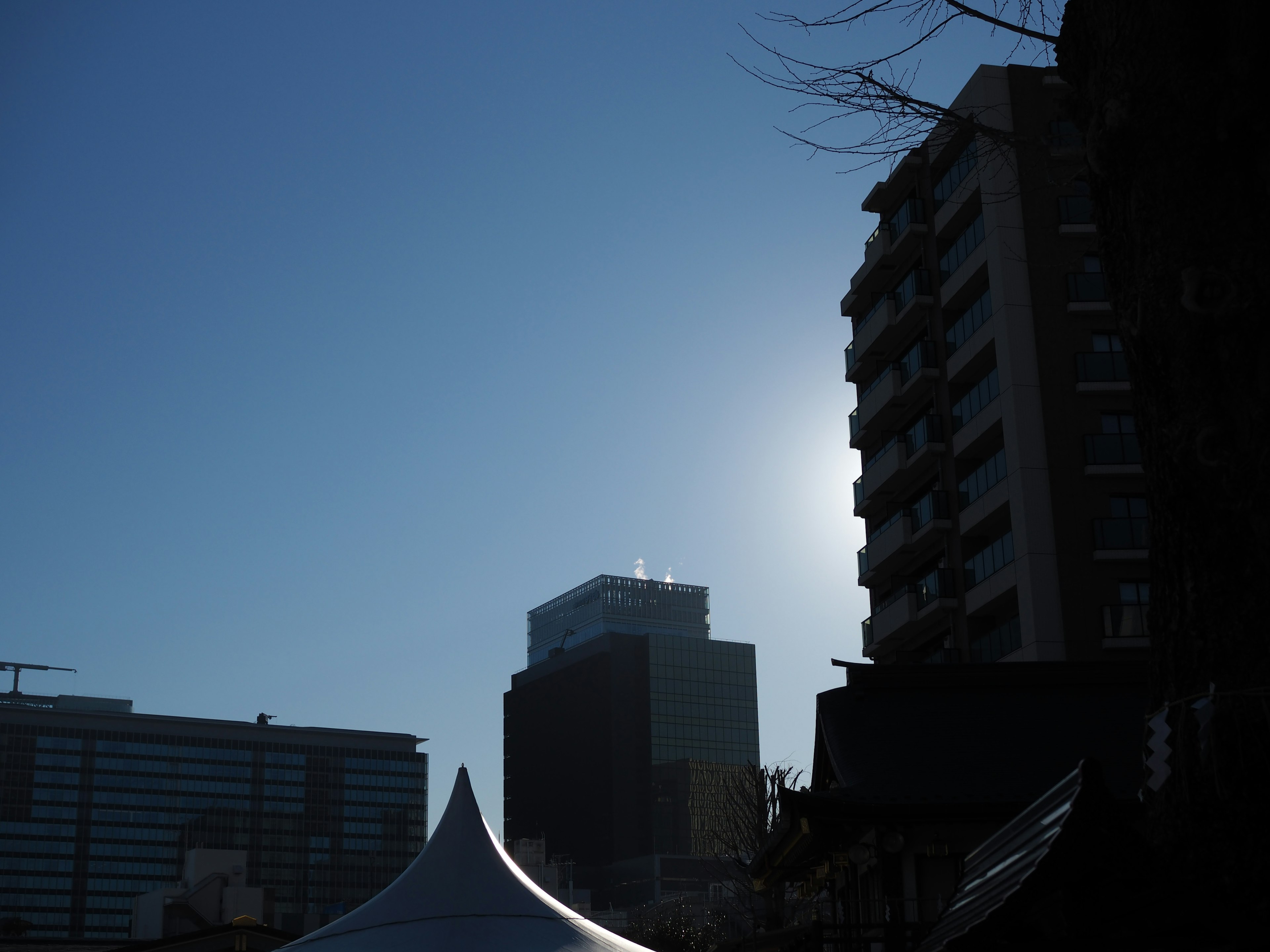 Silhouette di edifici e una tenda sotto un cielo blu