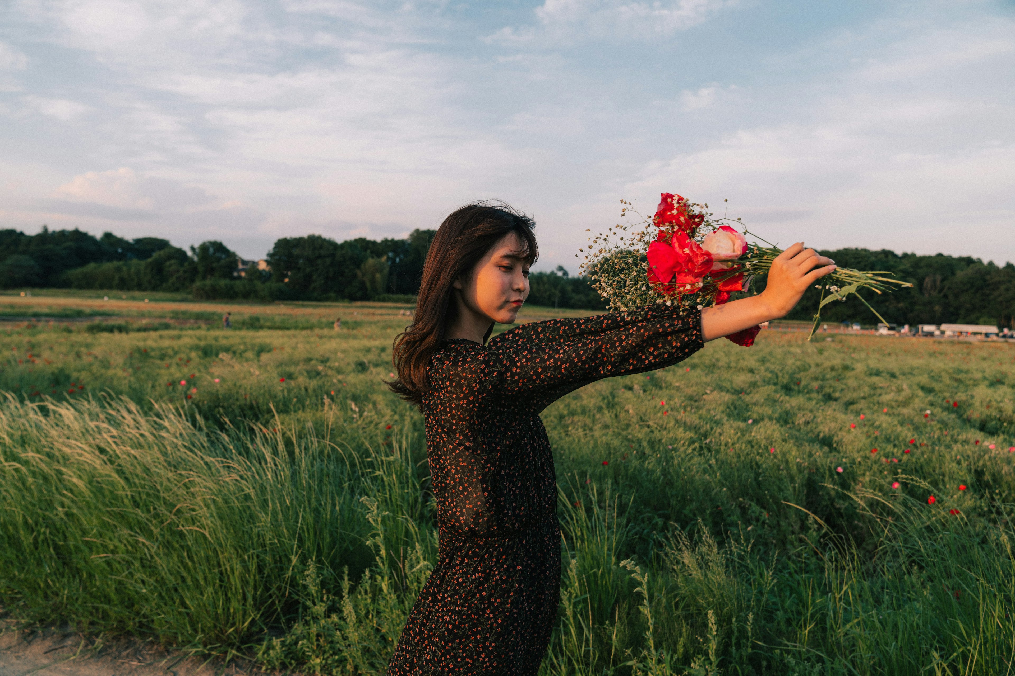 Mujer sosteniendo un ramo en un campo verde