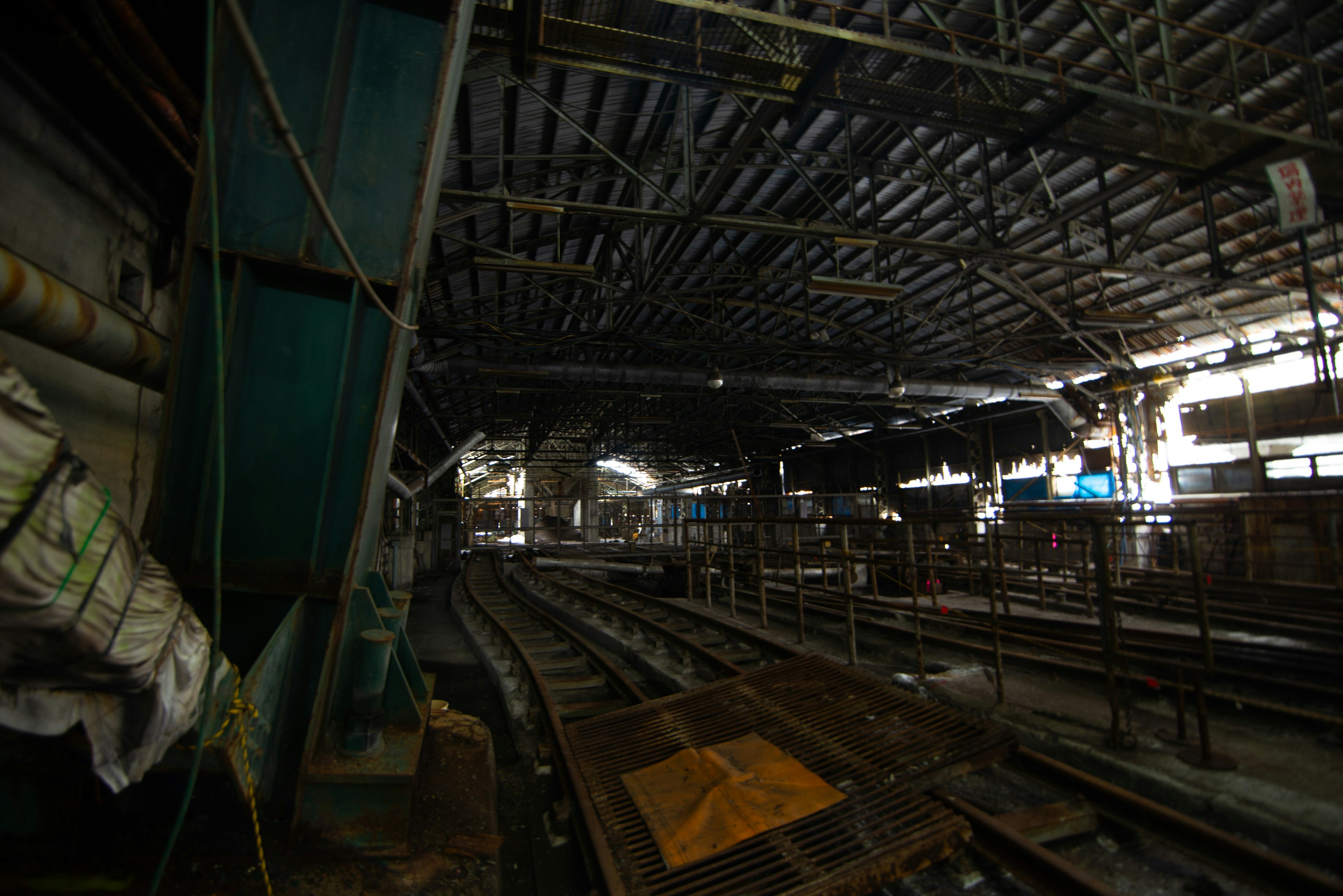 Intérieur d'une usine faiblement éclairée avec des voies ferrées et des structures industrielles