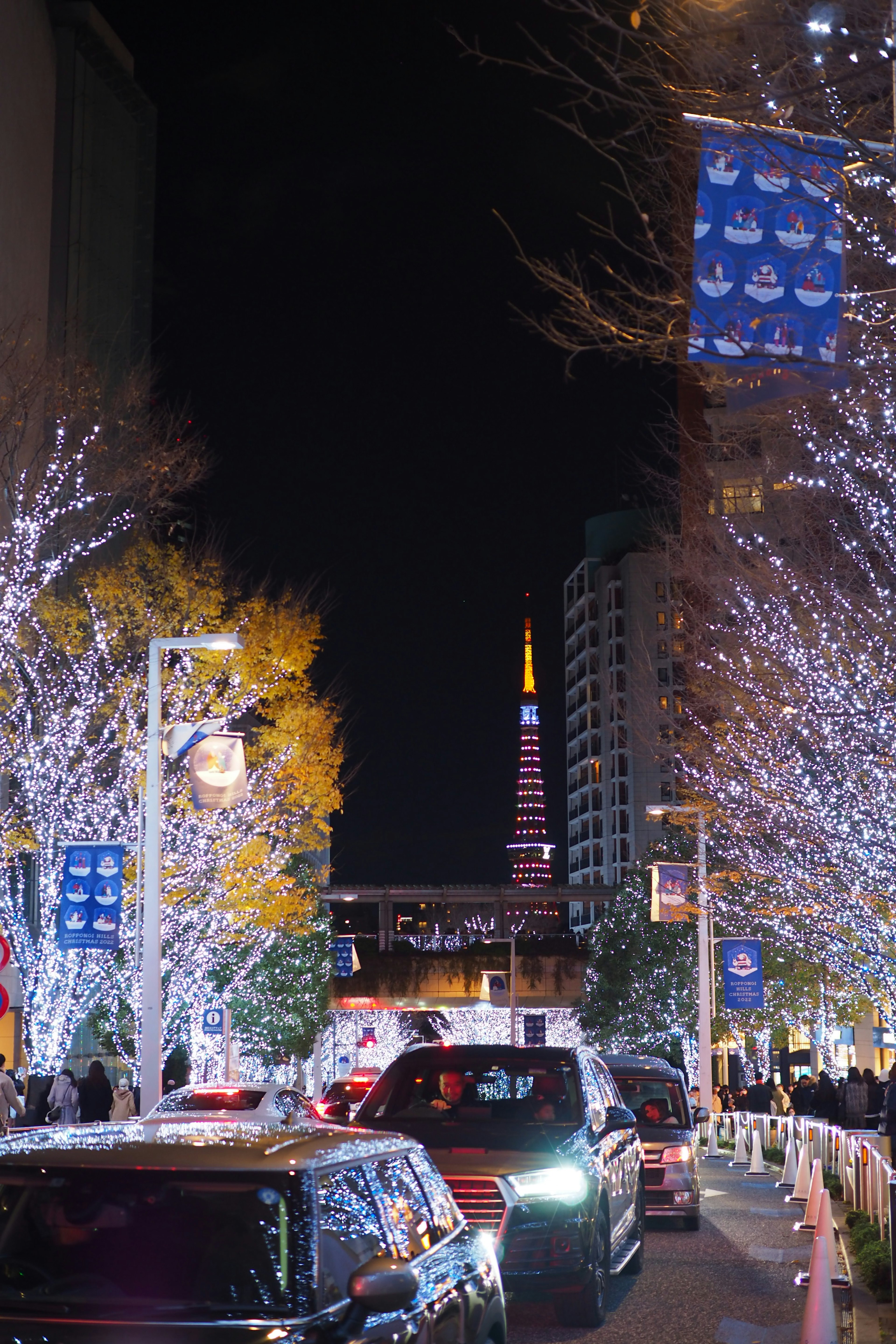 Torre de Tokio iluminada por la noche con luces festivas y calle concurrida