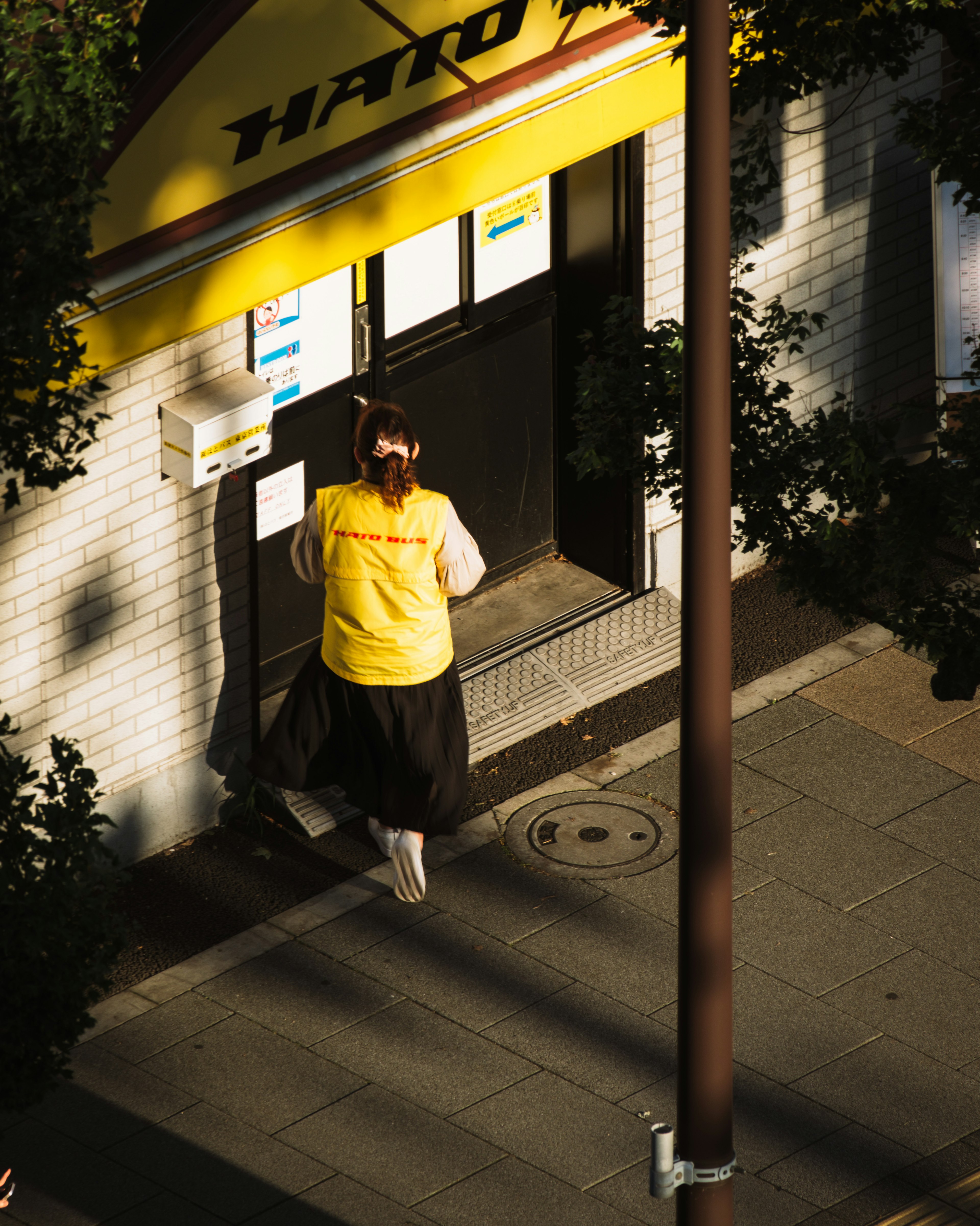 Una mujer con un chaleco amarillo caminando hacia la entrada de una tienda