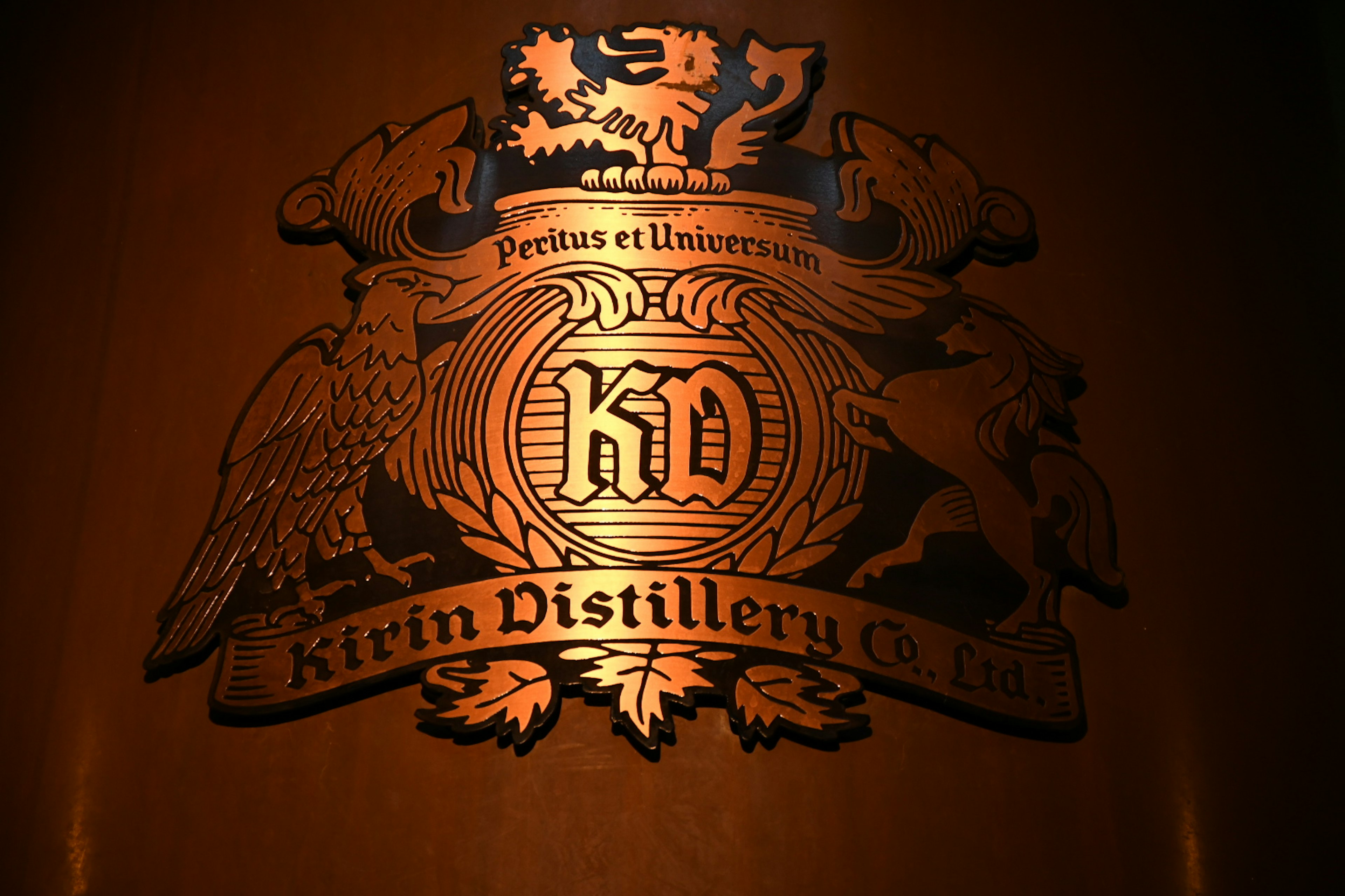 Logo de la distillerie Kirin en relief doré sur fond sombre