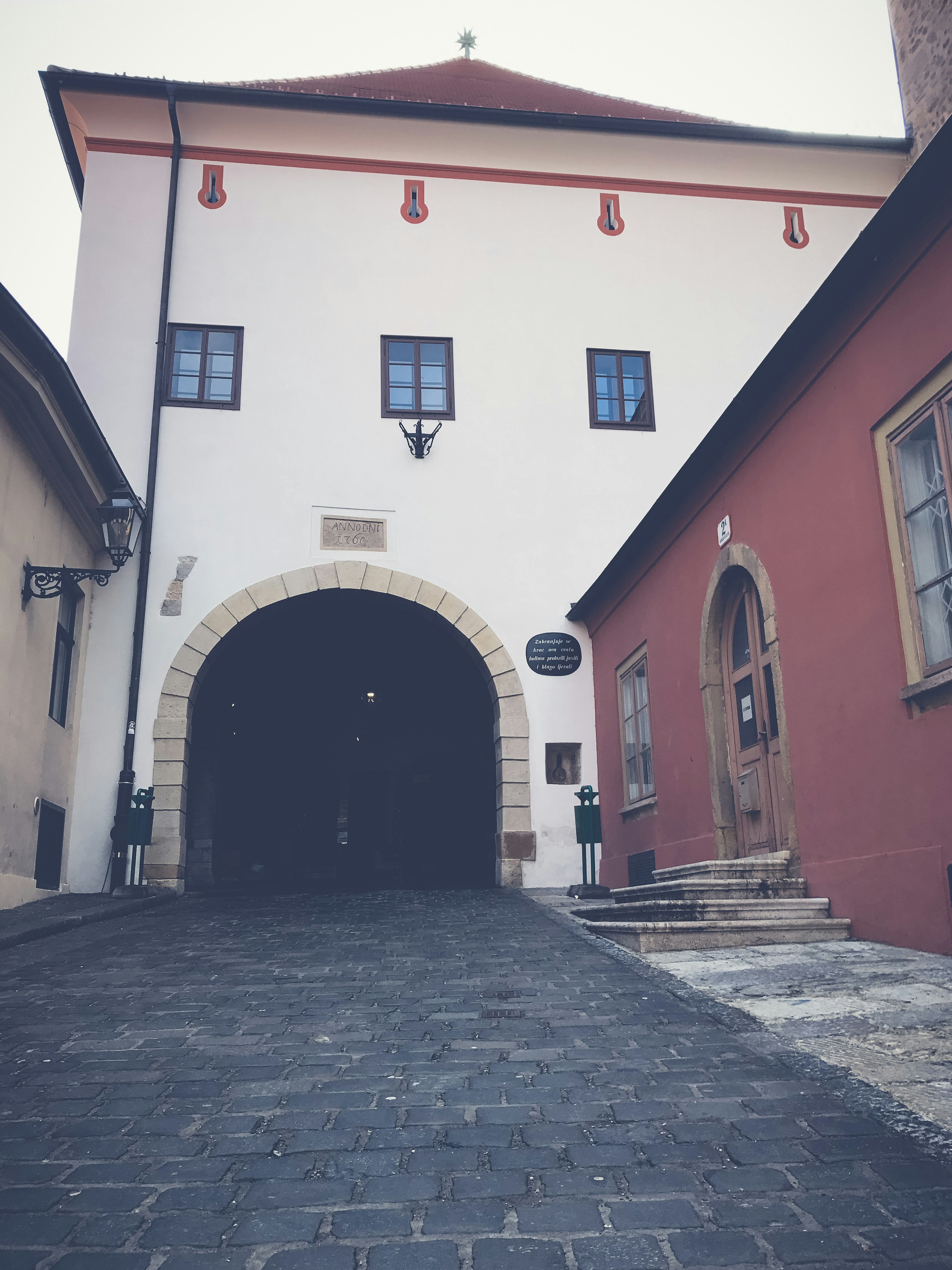 A scenic view featuring a white building with an archway and a red wall