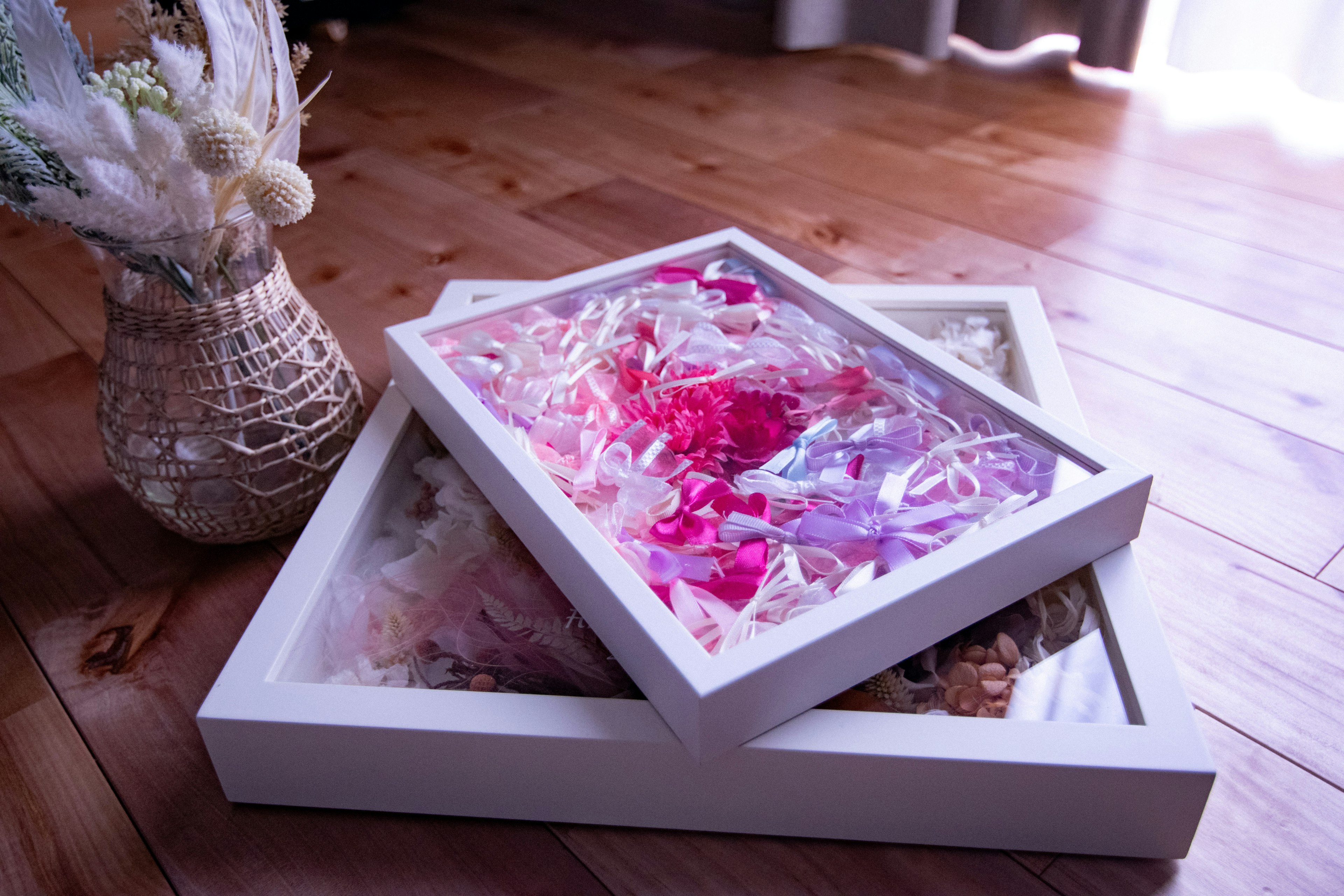 Pétales de fleurs colorés disposés dans des cadres blancs sur un sol en bois