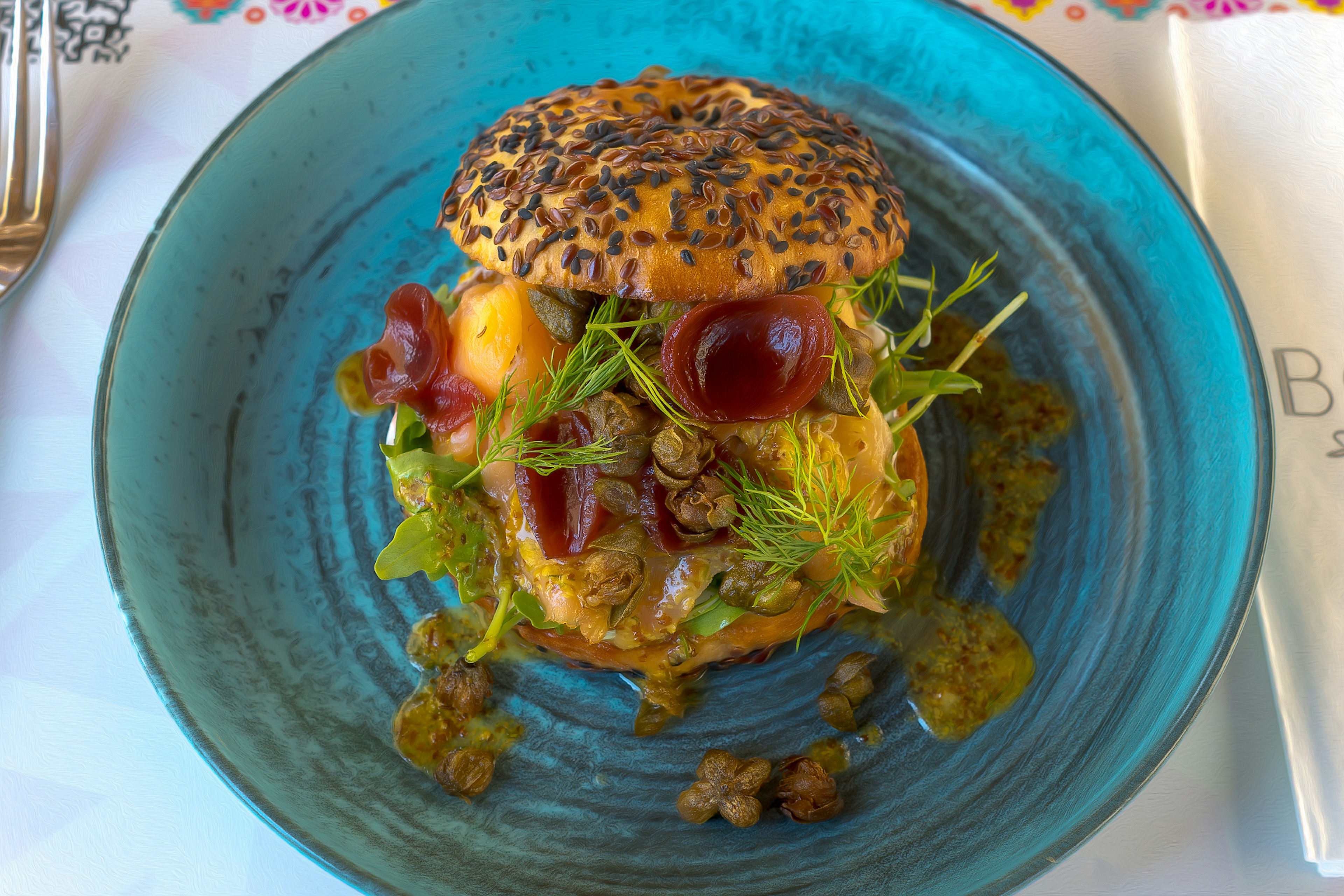 A colorful burger served on a blue plate with various toppings