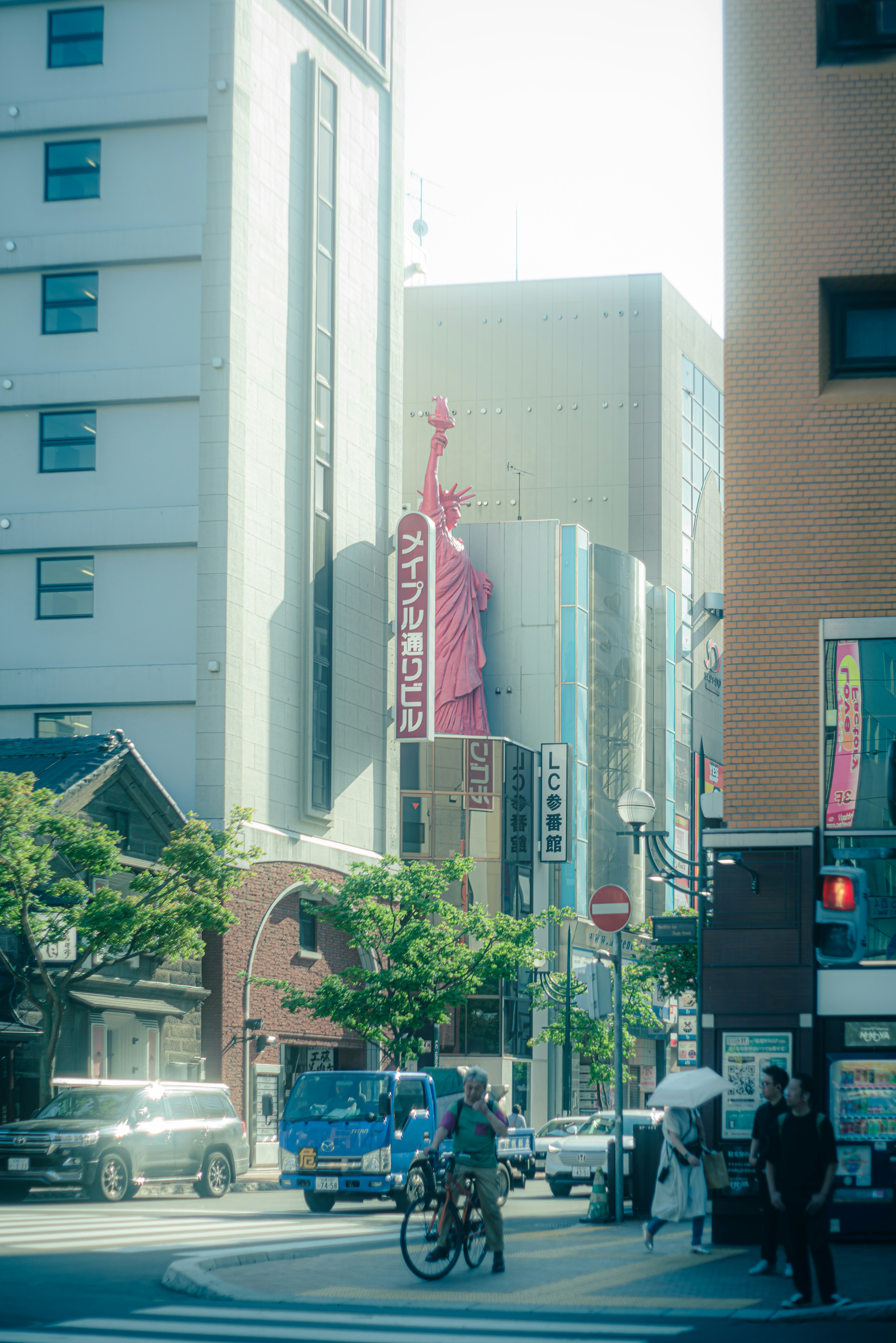 街角に立つ自由の女神像と周囲のビル群