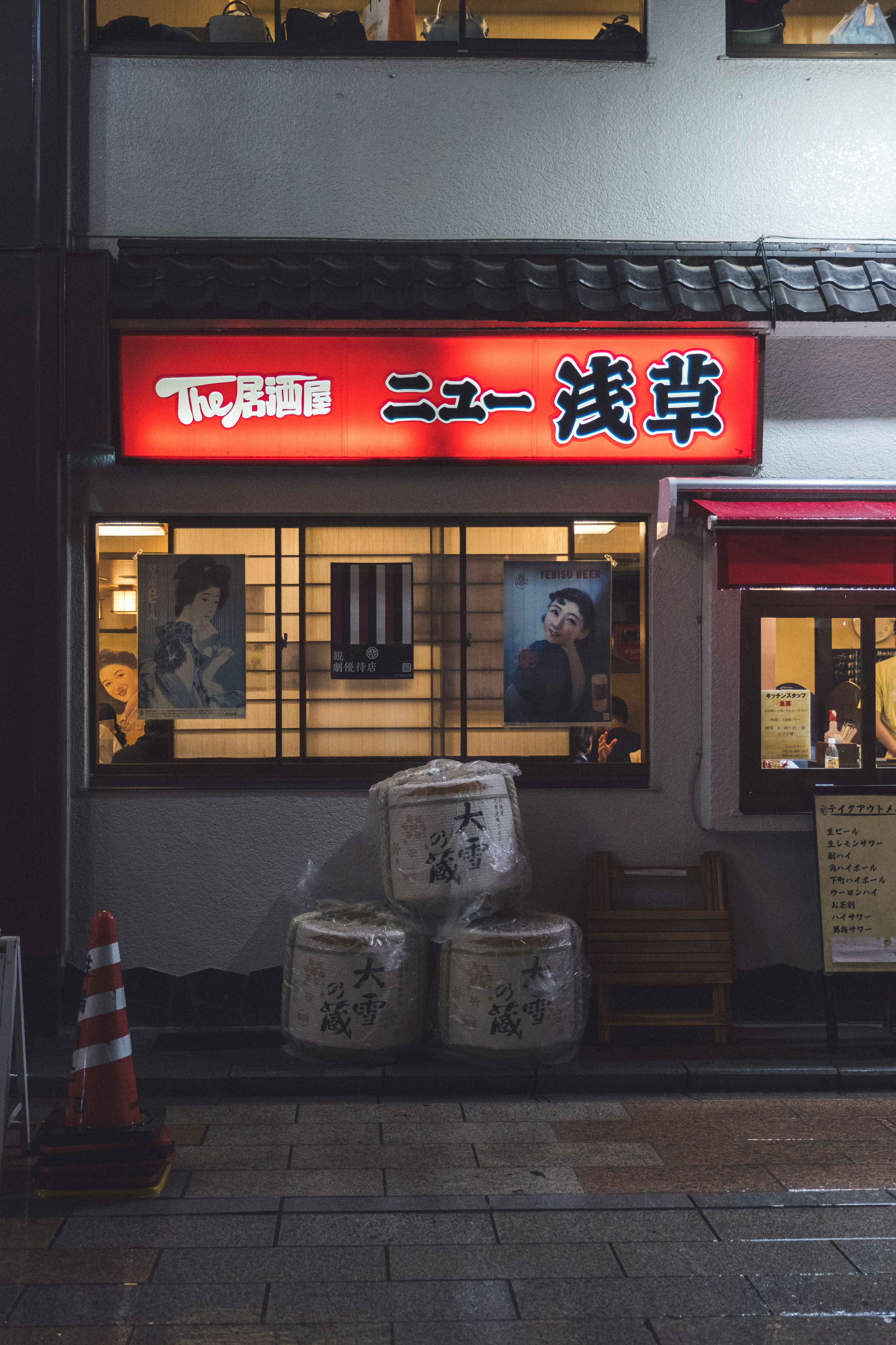 Exterior of a Japanese restaurant with a red sign and stacked goods