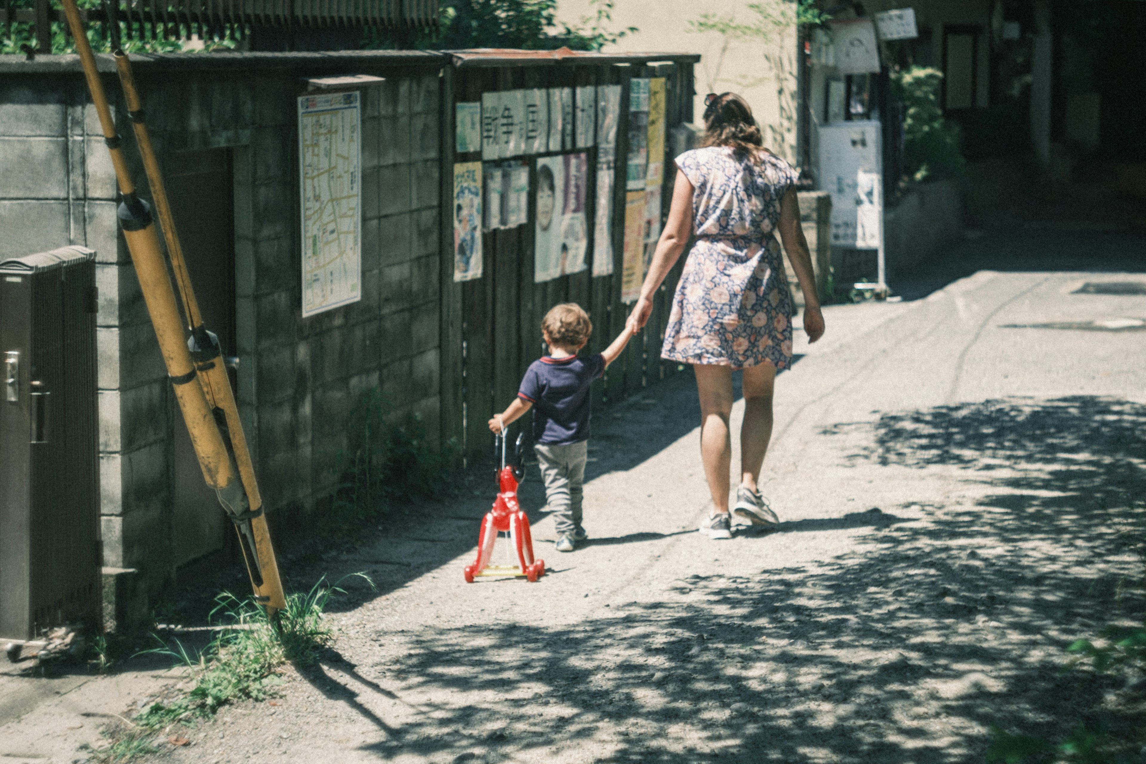 Eine Mutter und ihr Kind, die Hand in Hand auf einem sonnigen Weg gehen