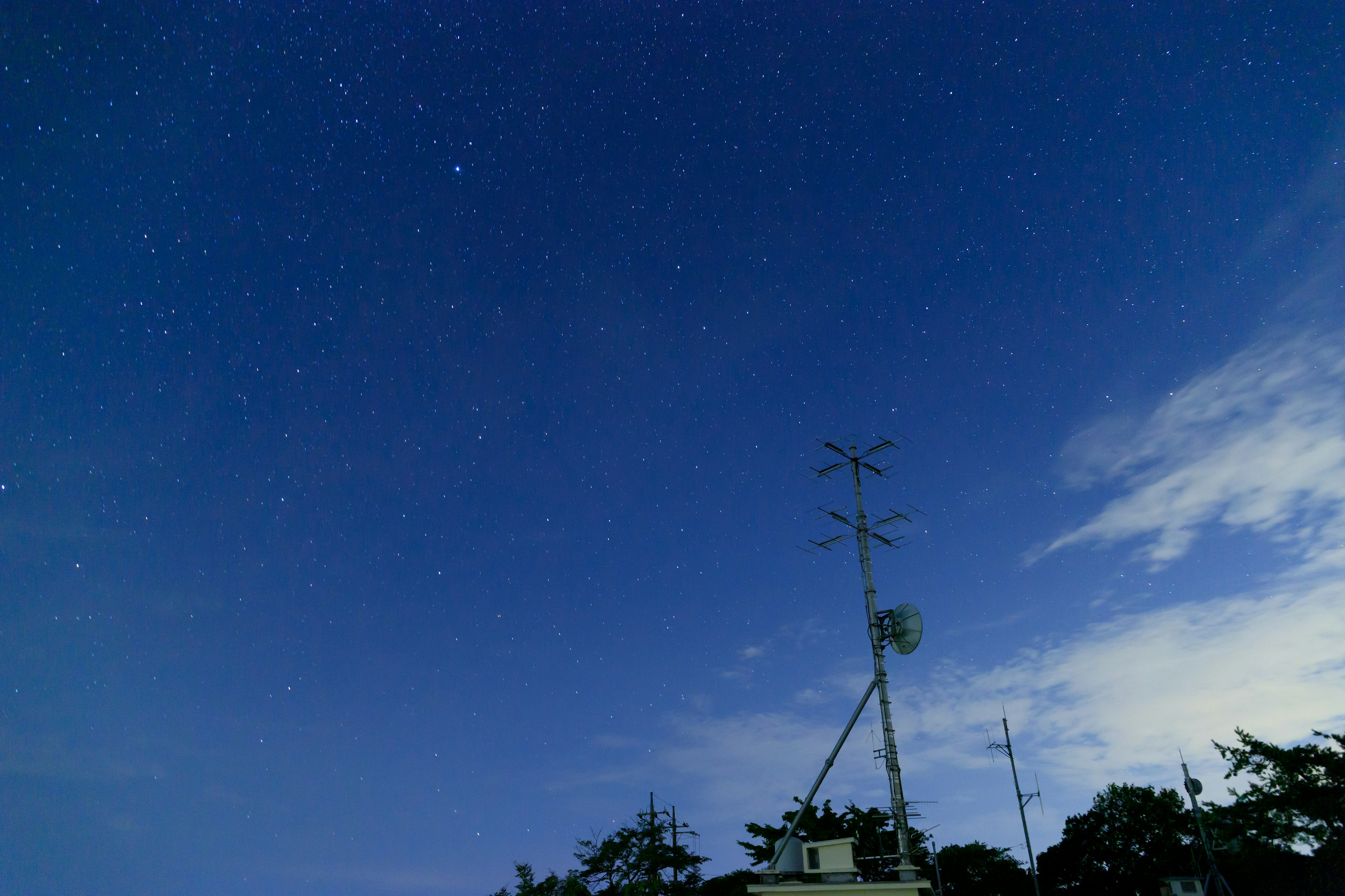 Cielo notturno stellato con una torre di comunicazione