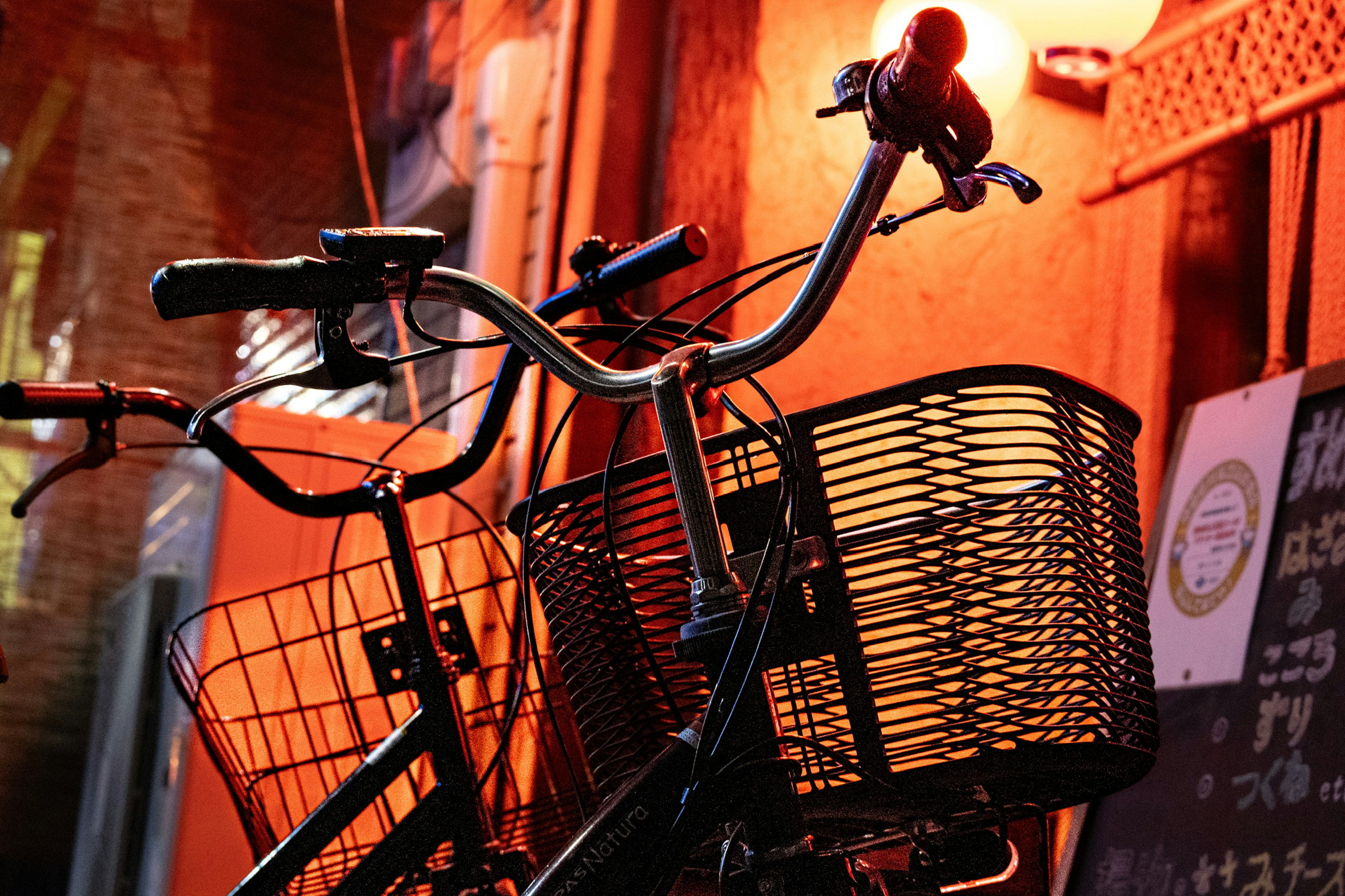 Bicycle handlebars and basket leaning against an orange wall