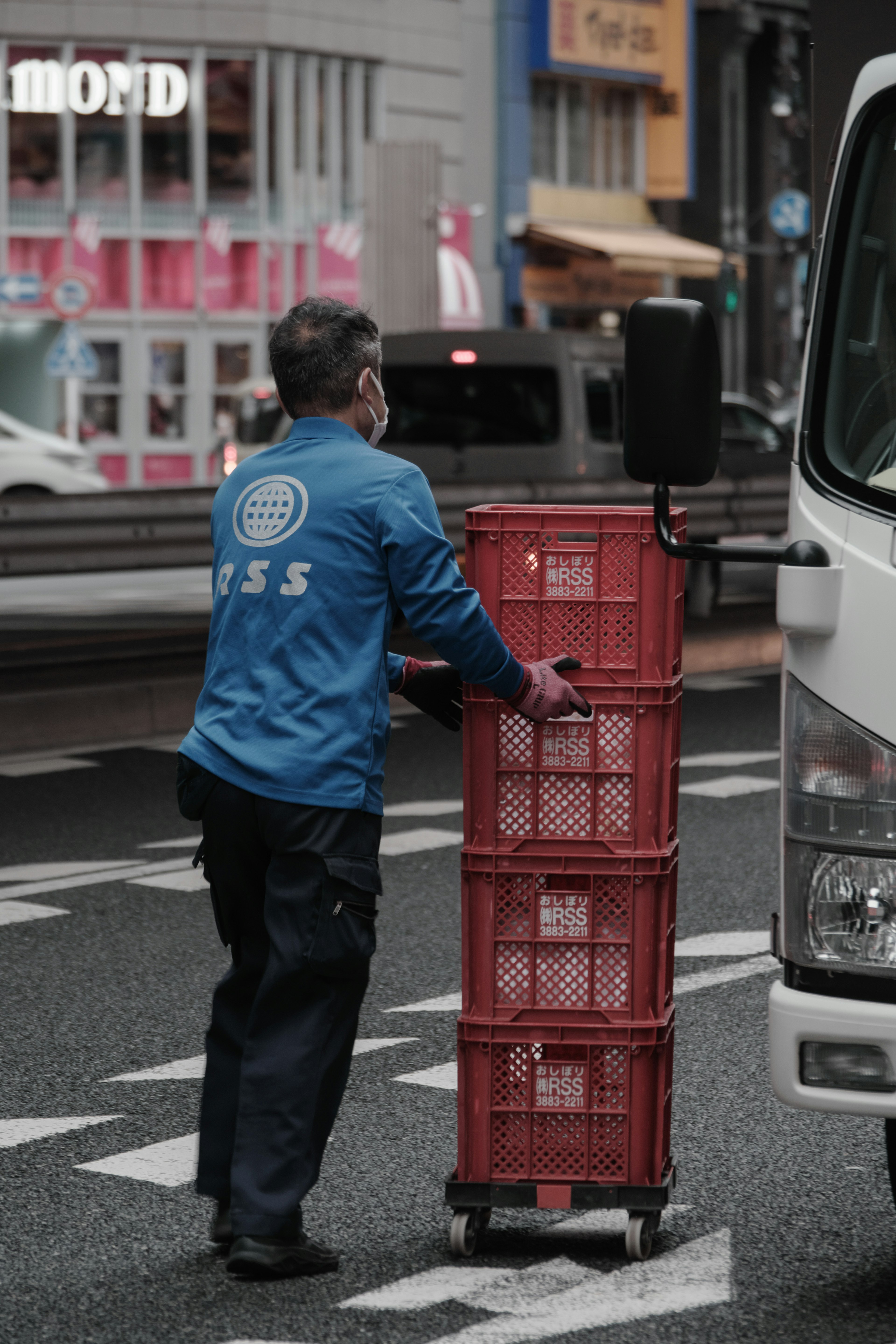 Lavoratore che spinge casse rosse in una strada della città