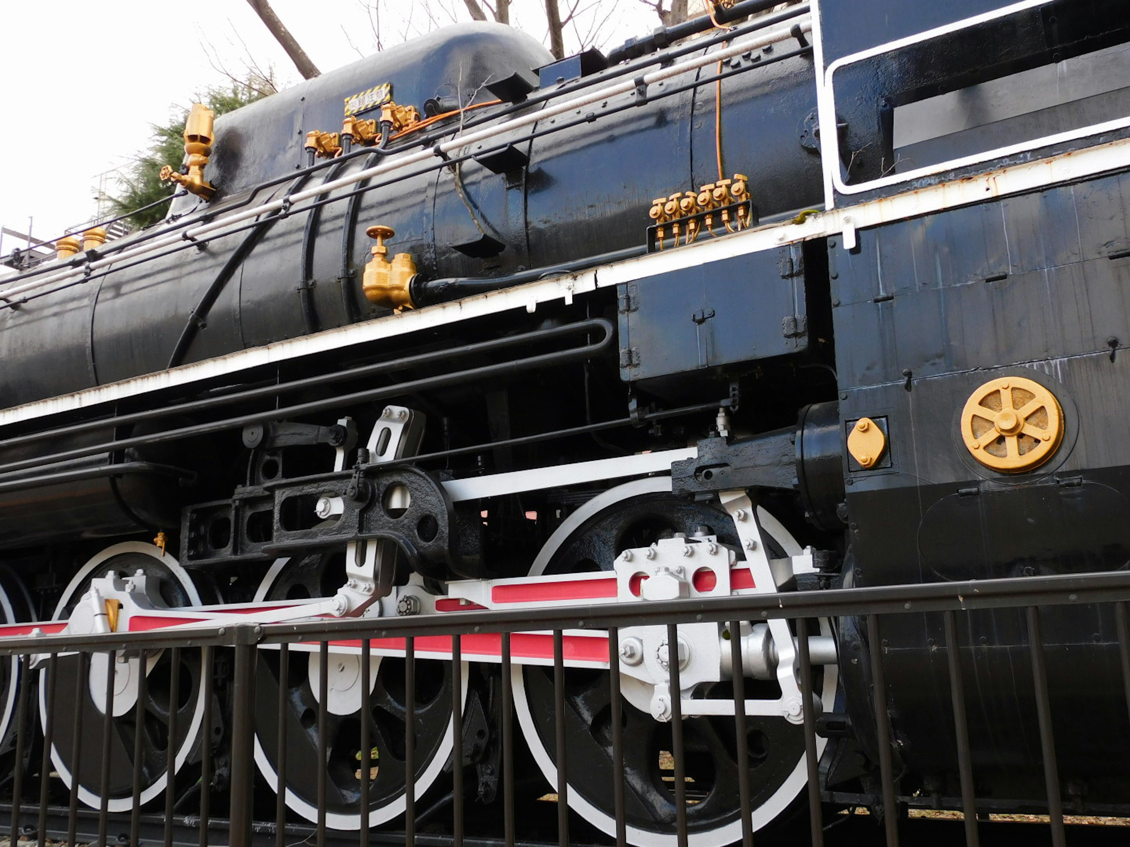 Primer plano de una locomotora de vapor negra con acentos dorados y ruedas blancas