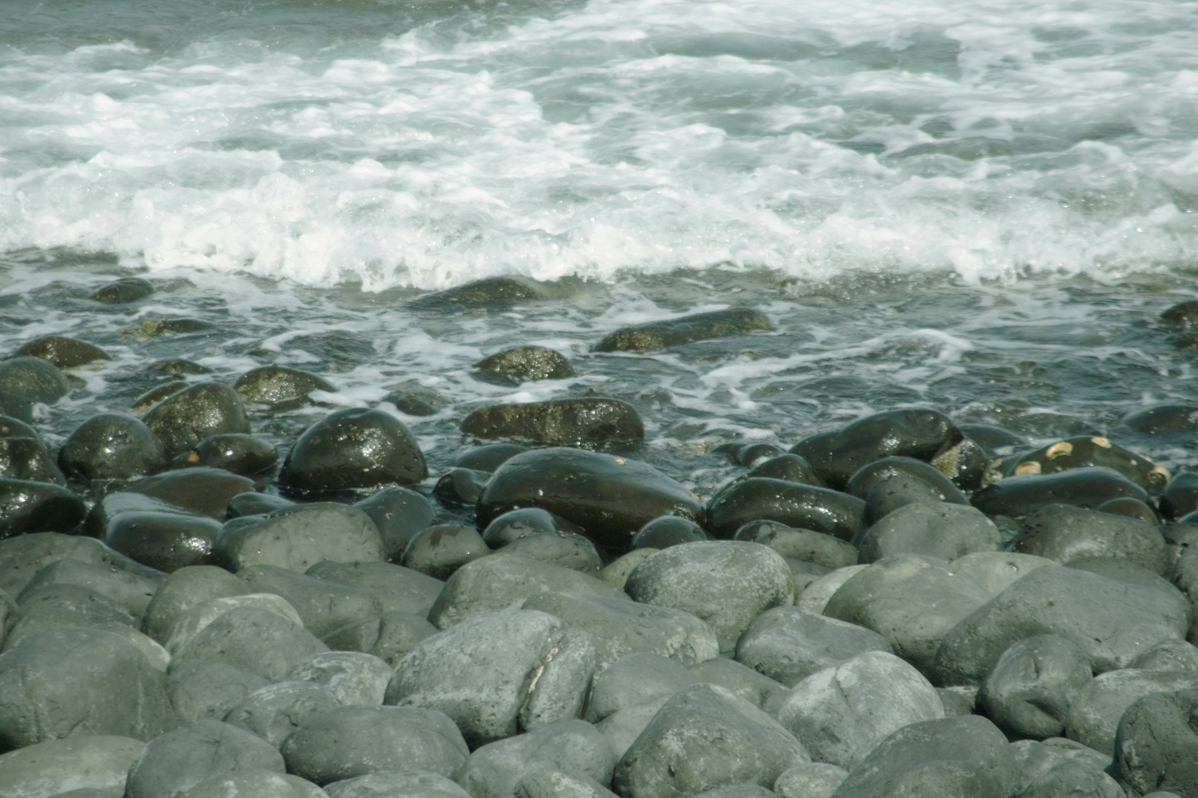 Felsiger Strand mit brechenden Wellen